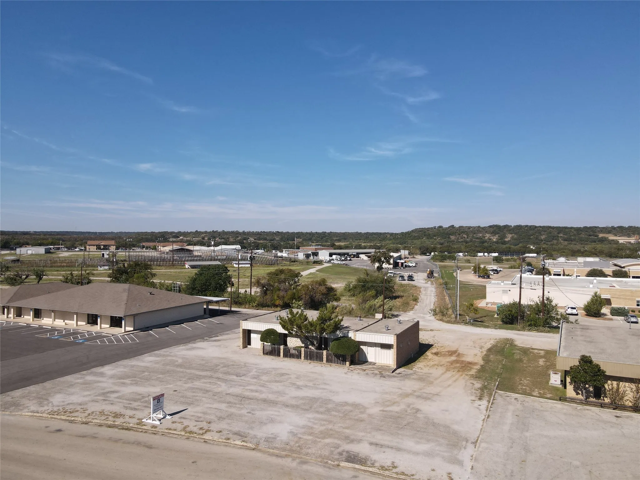 Expansive paved lot with multi-vehicle capacity and a single-story commercial structure featuring a flat roof and masonry exterior
