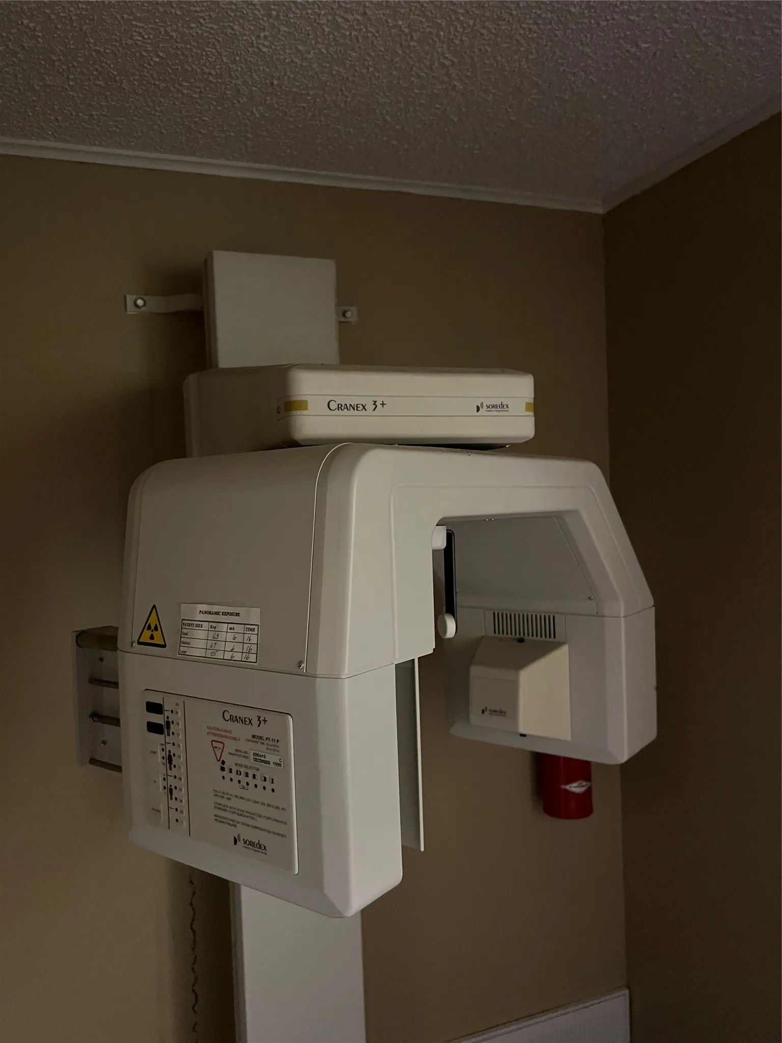 Wall-mounted Soredex Cranex 3+ panoramic imaging system featuring a white synthetic housing, integrated control panel, and specialized radiation shielding​​‌​​​​‌​​‌‌​‌‌​​​‌‌​‌​‌​‌​​​‌​​ hardware