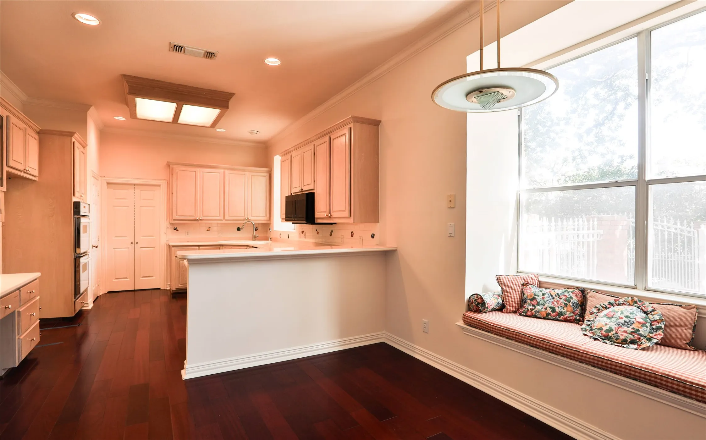 Kitchen featuring wood-finish flooring, custom cabinetry, a peninsula counter, recessed lighting, and a built-in window seat