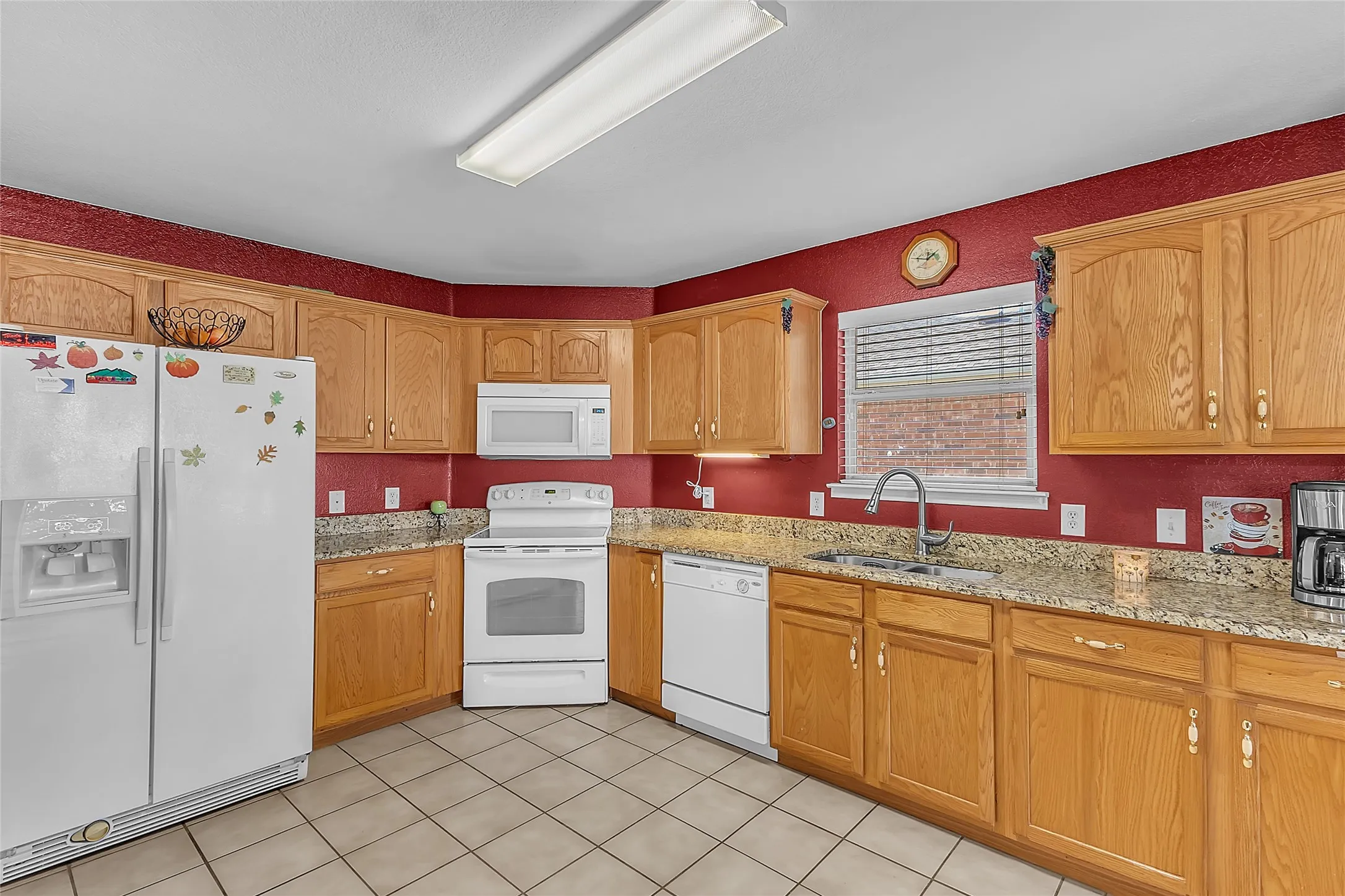 Kitchen wraparound counters, white fridge, and window over sink