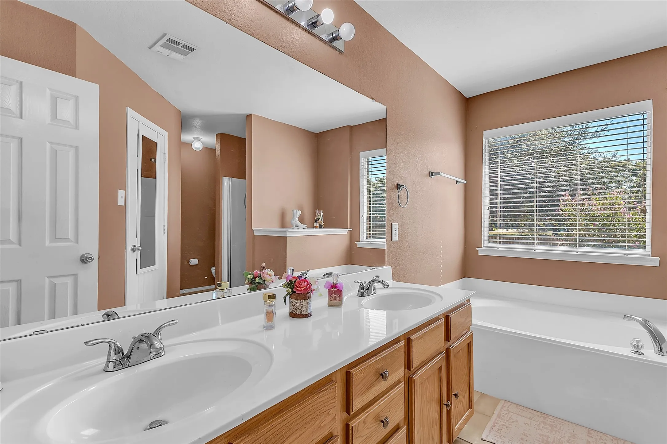 Primary bath double vanity, soaking tub under window, tile surround