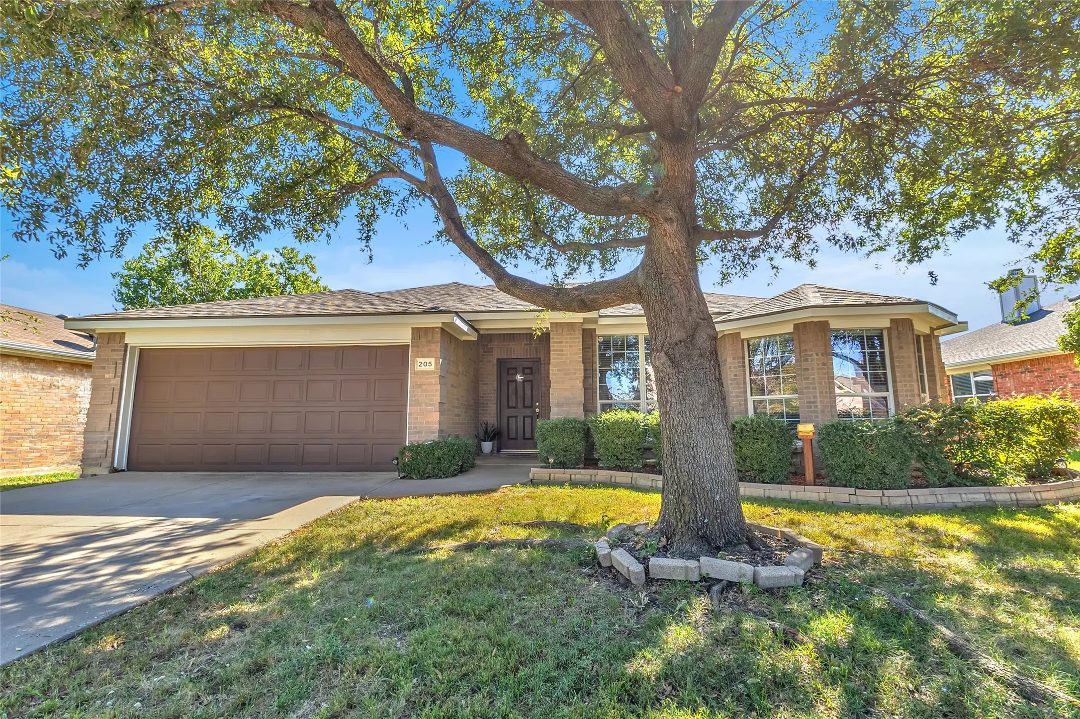 Curb view of 205 Tripp Trl: brick home, bay window, landscaped beds