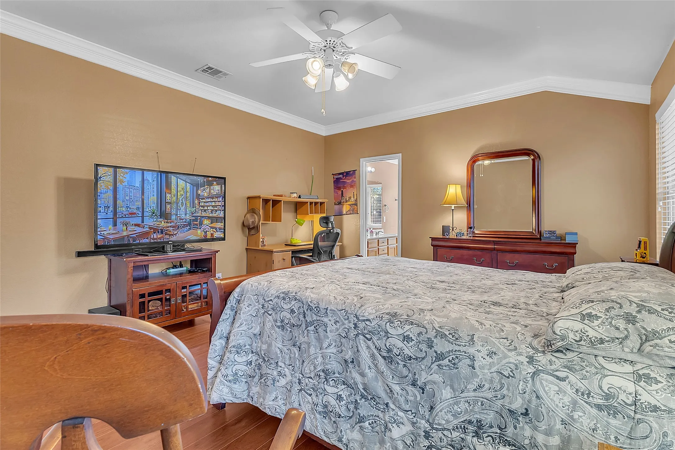 Primary bedroom with manufactured-wood floors, ceiling fan, and ensuite access