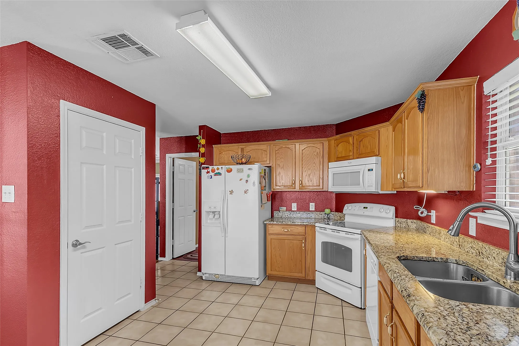 Kitchen L-layout: oak cabinets, white appliances, stainless double sink