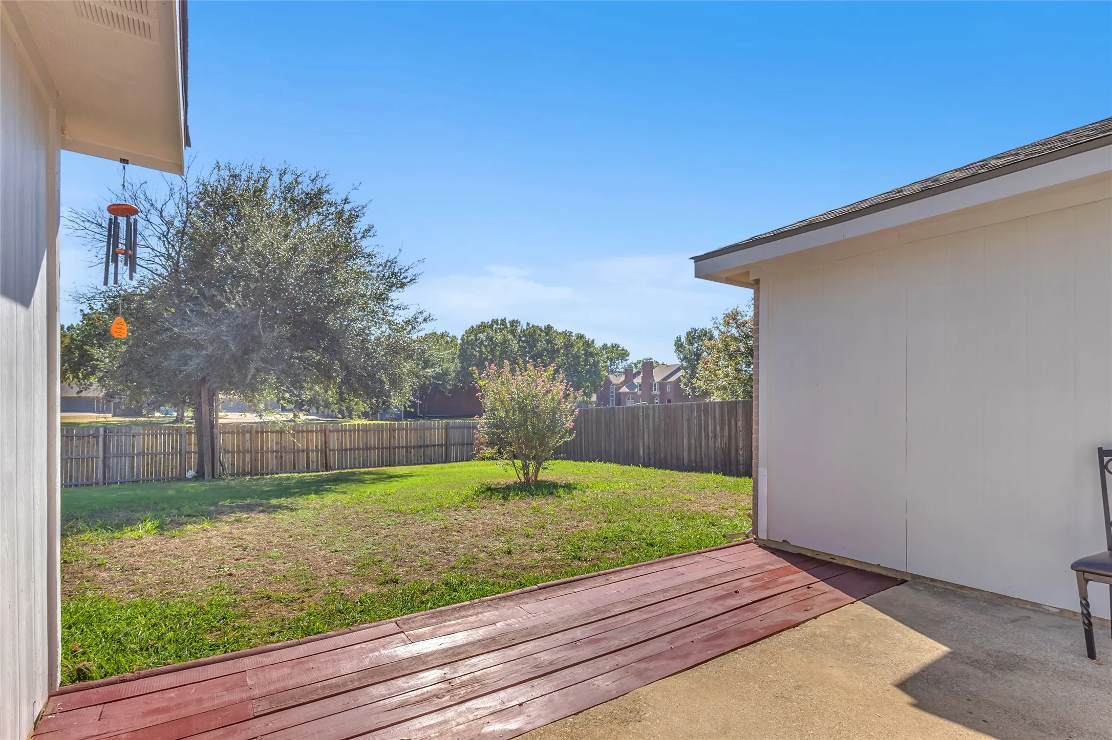 Backyard from patio: wood deck edge, lawn, and privacy fence — Denton
