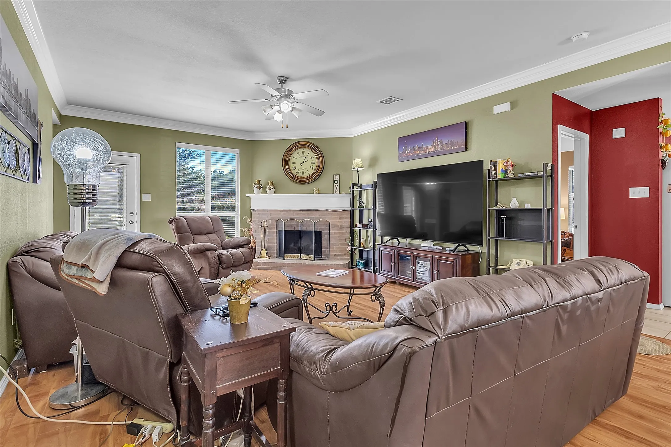 Living room facing brick fireplace, TV wall, and manufactured-wood floors