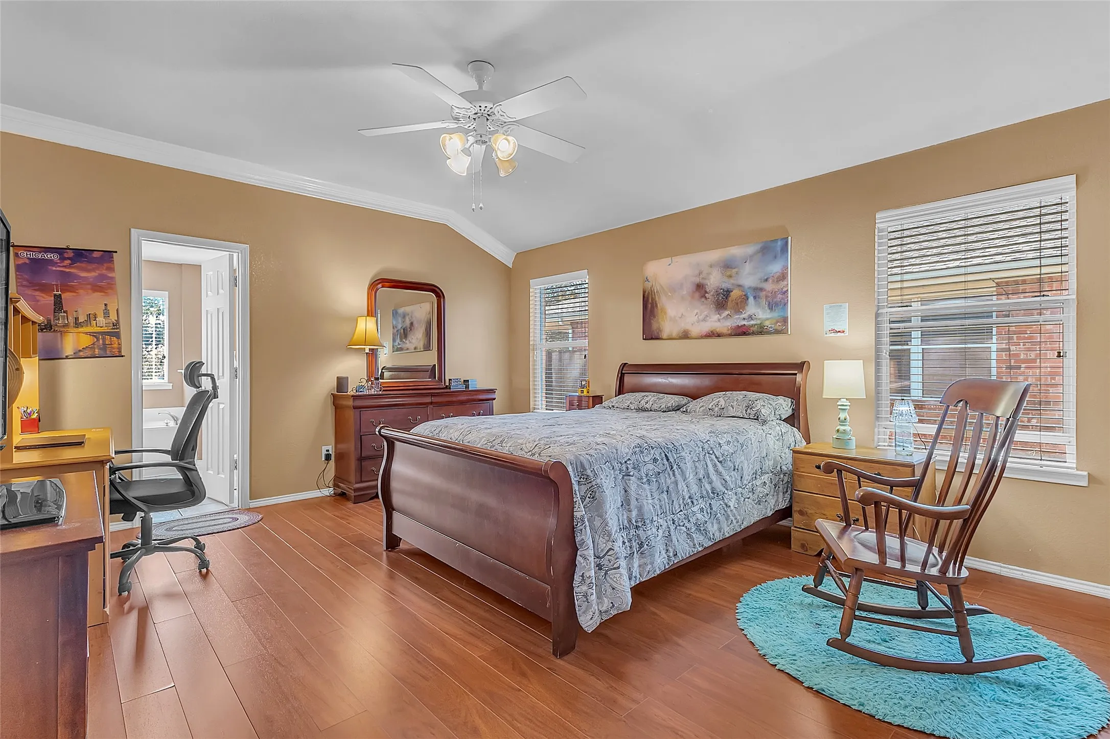 Primary bedroom: manufactured-wood floors, ceiling fan, windows to backyard