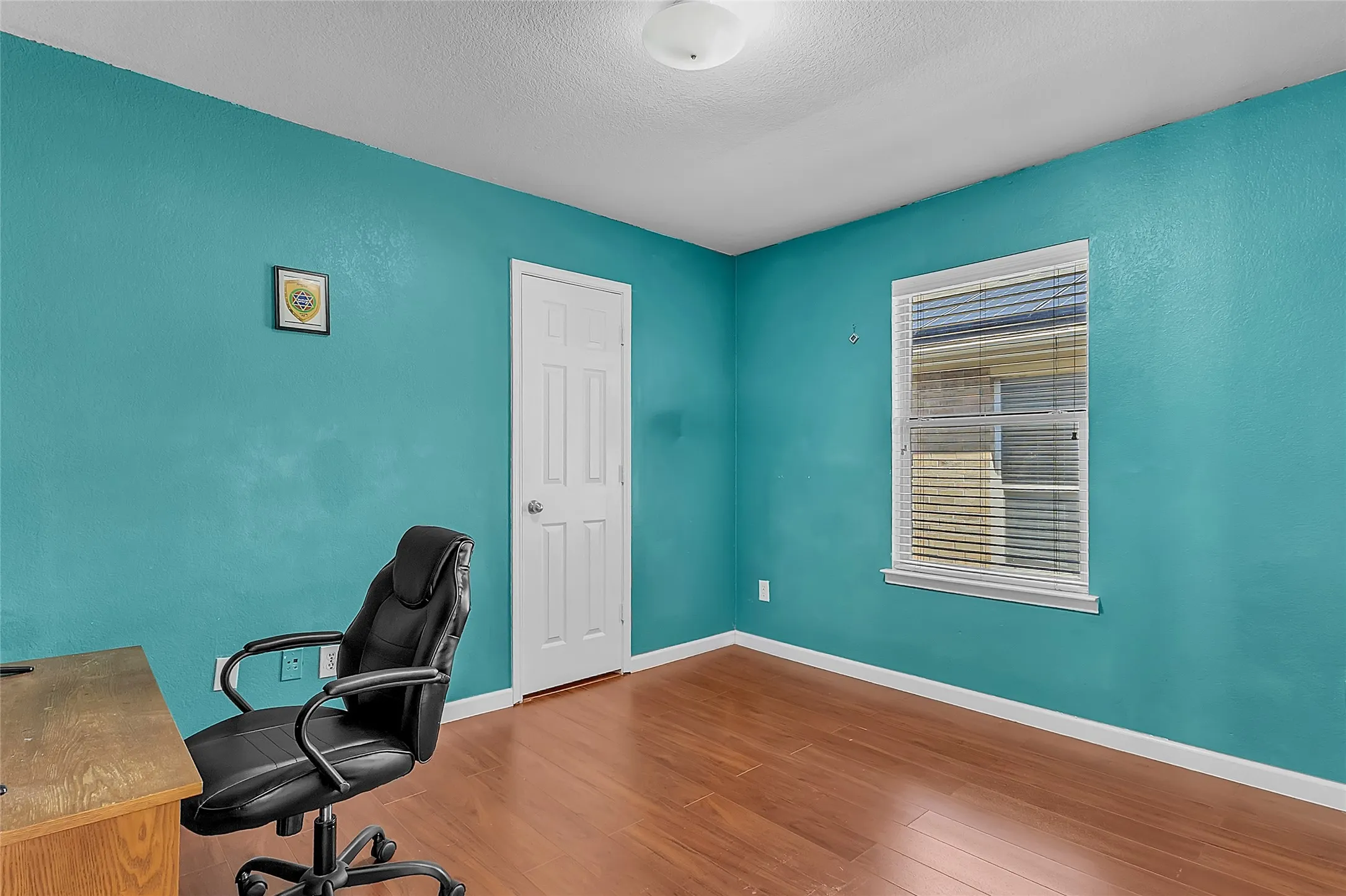 Secondary bedroom with teal walls, manufactured-wood floors, and window — Denton