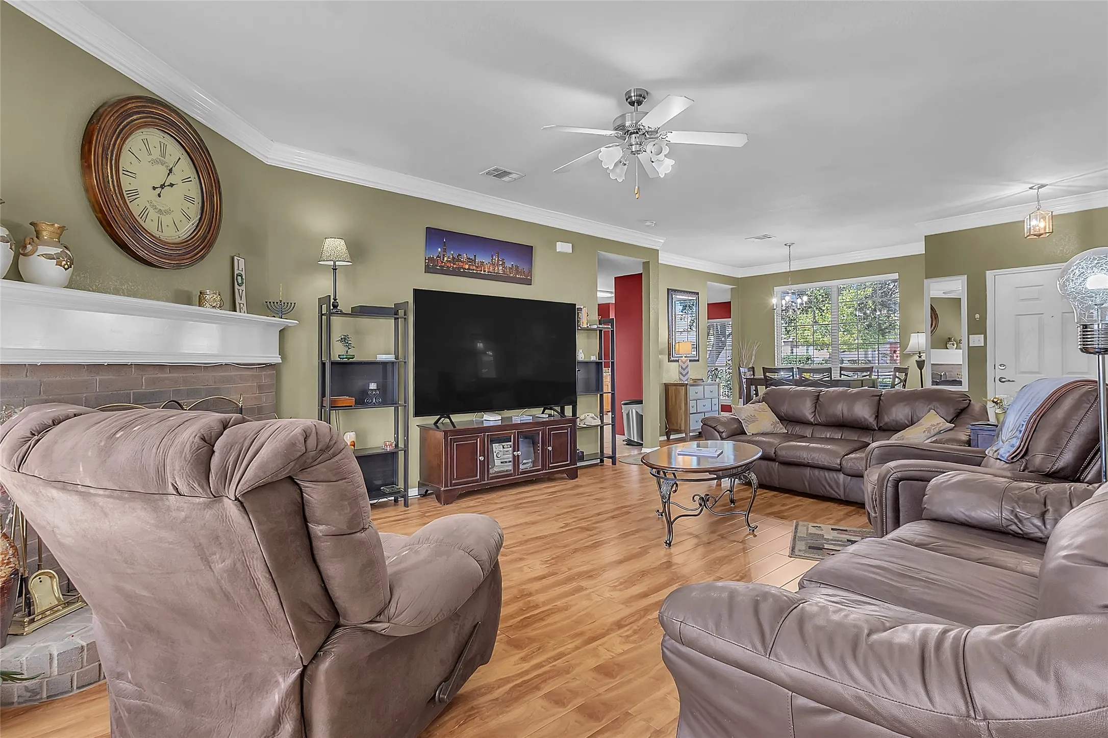 Living room open to dining: brick fireplace, manufactured-wood floors — Denton