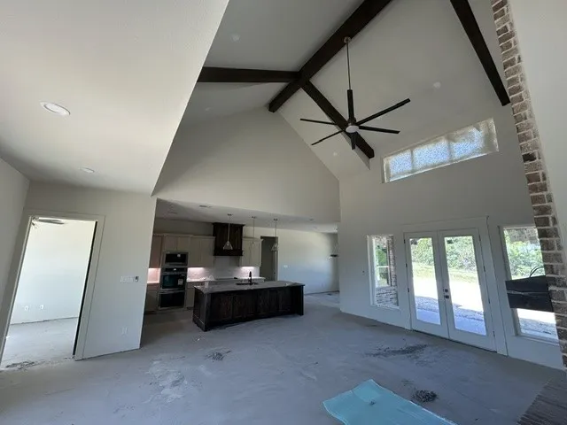 Vaulted ceilings with exposed wood beams, central kitchen island, recessed lighting, and brick-accented fireplace surround