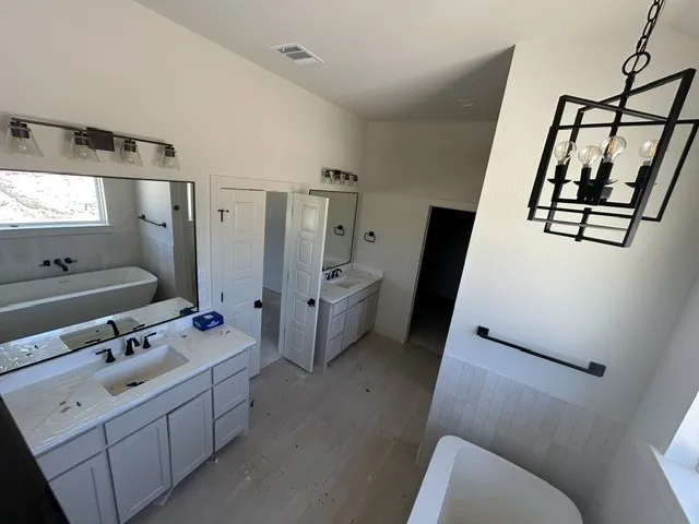 Dual vanity area featuring quartz countertops, undermount sinks, matte black plumbing fixtures, large-format tile flooring, and geometric pendant lighting