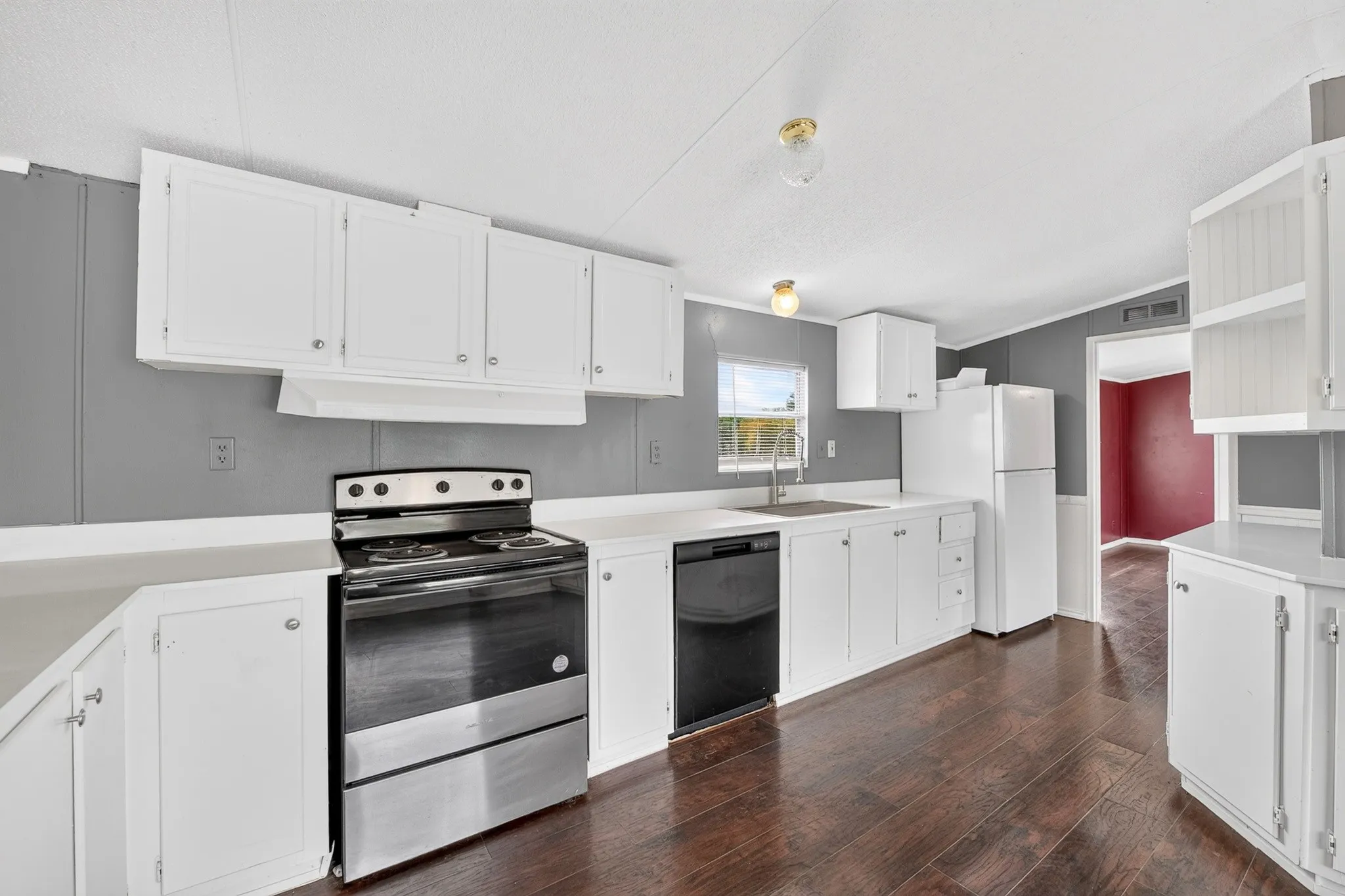 Kitchen featuring white cabinetry, dark wood-finish flooring, stainless steel electric range, black dishwasher, and solid-surface countertops