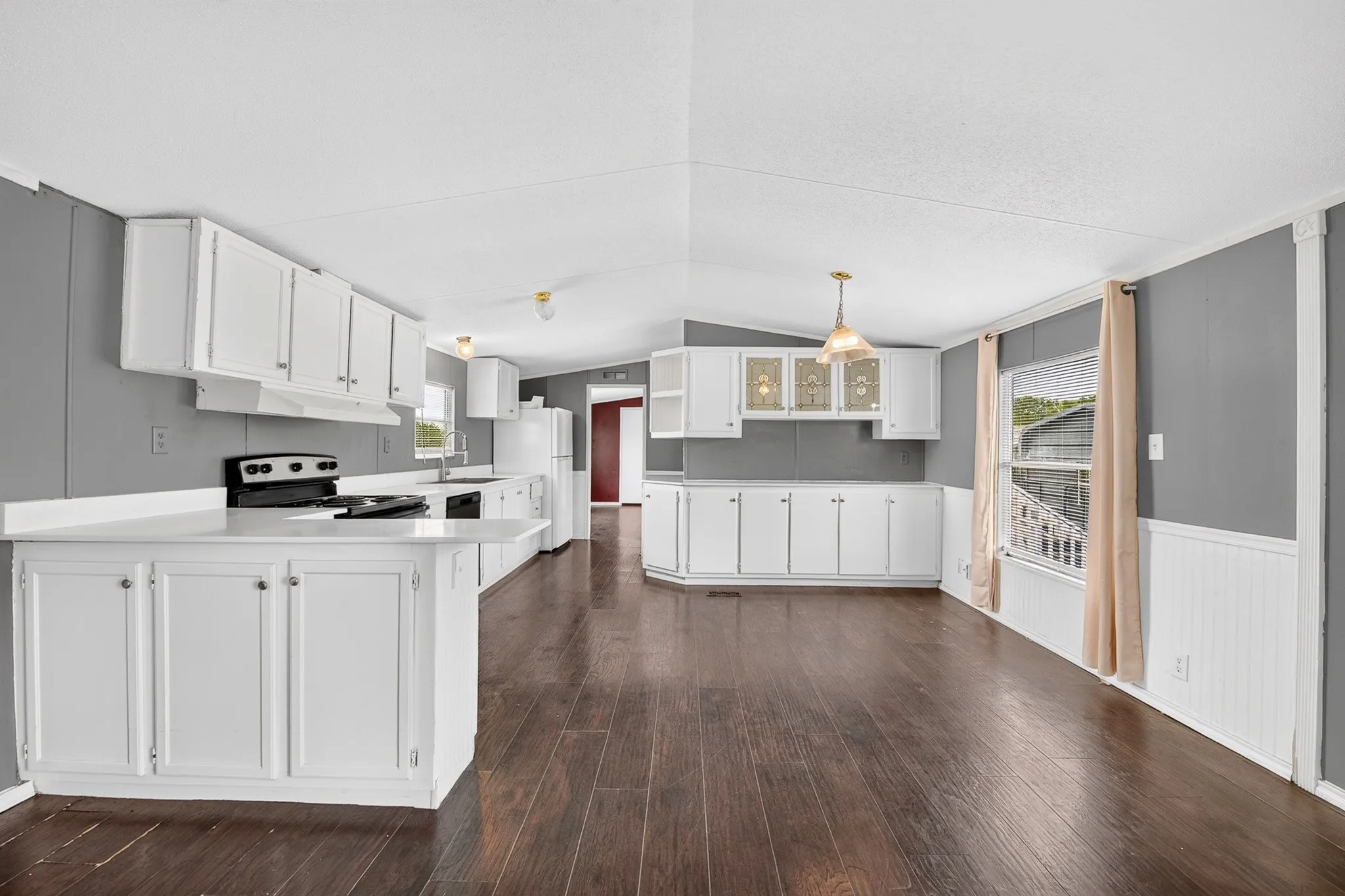Kitchen featuring wood-finish flooring, white cabinetry, integrated upper glass-panel displays, and solid-surface countertops