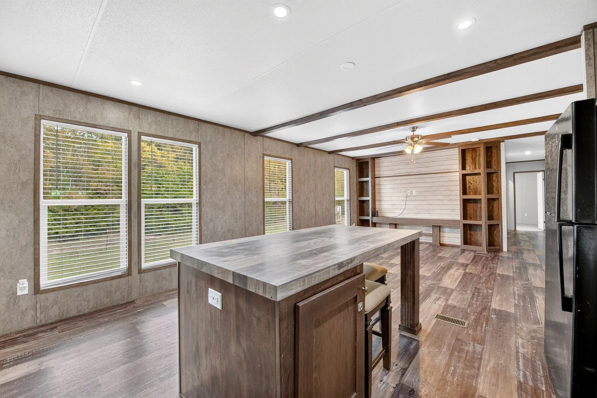 Kitchen featuring a central island with wood-finish cabinetry, wood-finish flooring, recessed ceiling lighting, decorative exposed ceiling beams, and built-in shelving