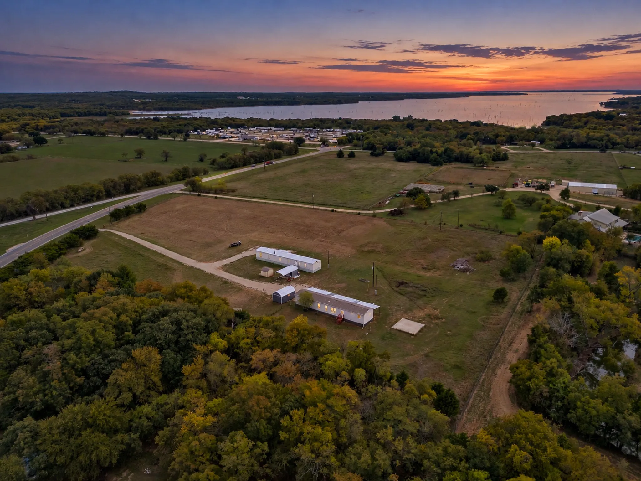 Expansive acreage featuring multiple structures, cleared pasture land, and mature tree clusters