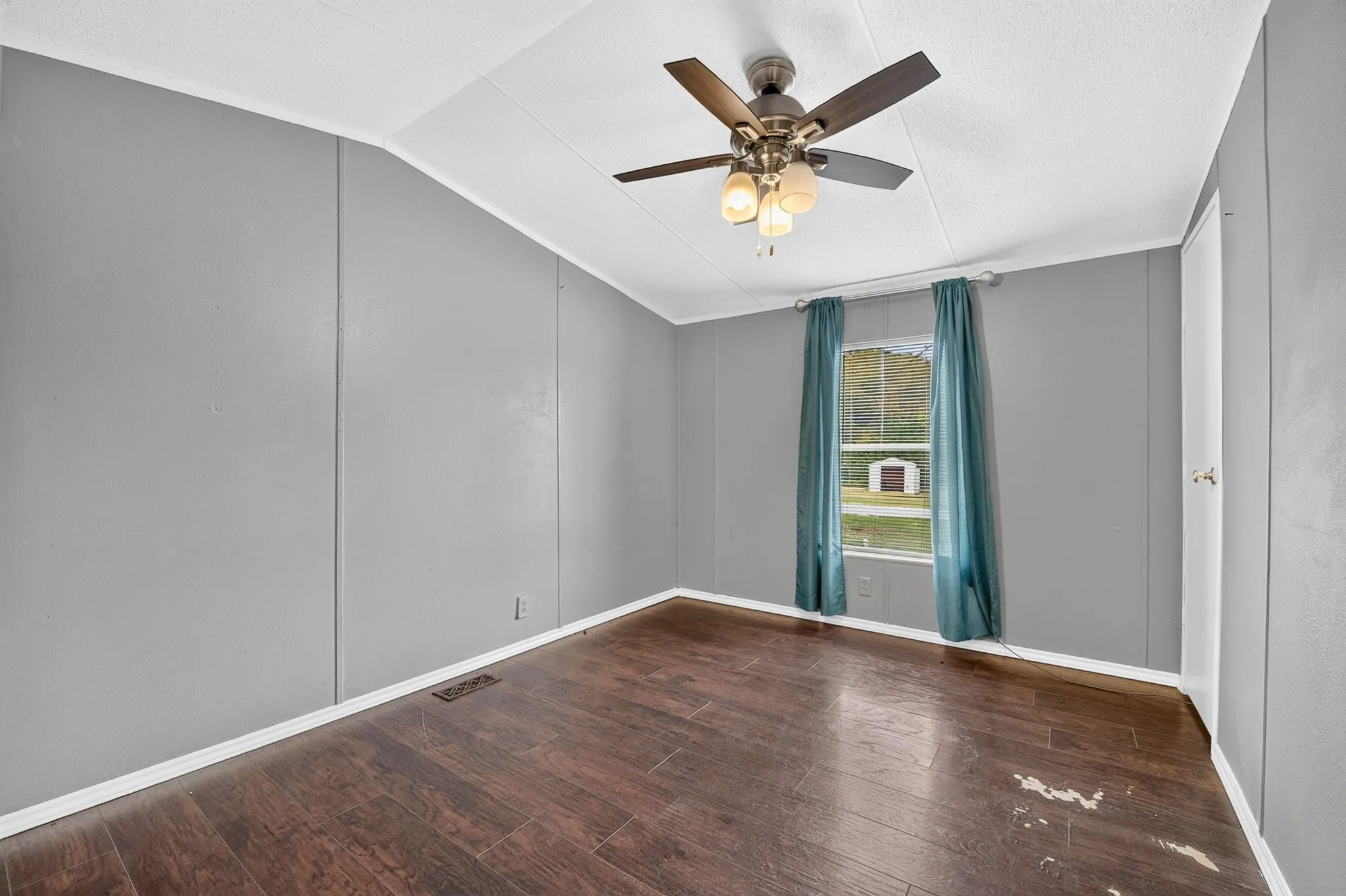 Room featuring wood-finish flooring, neutral-toned walls, and a ceiling fan with integrated lighting