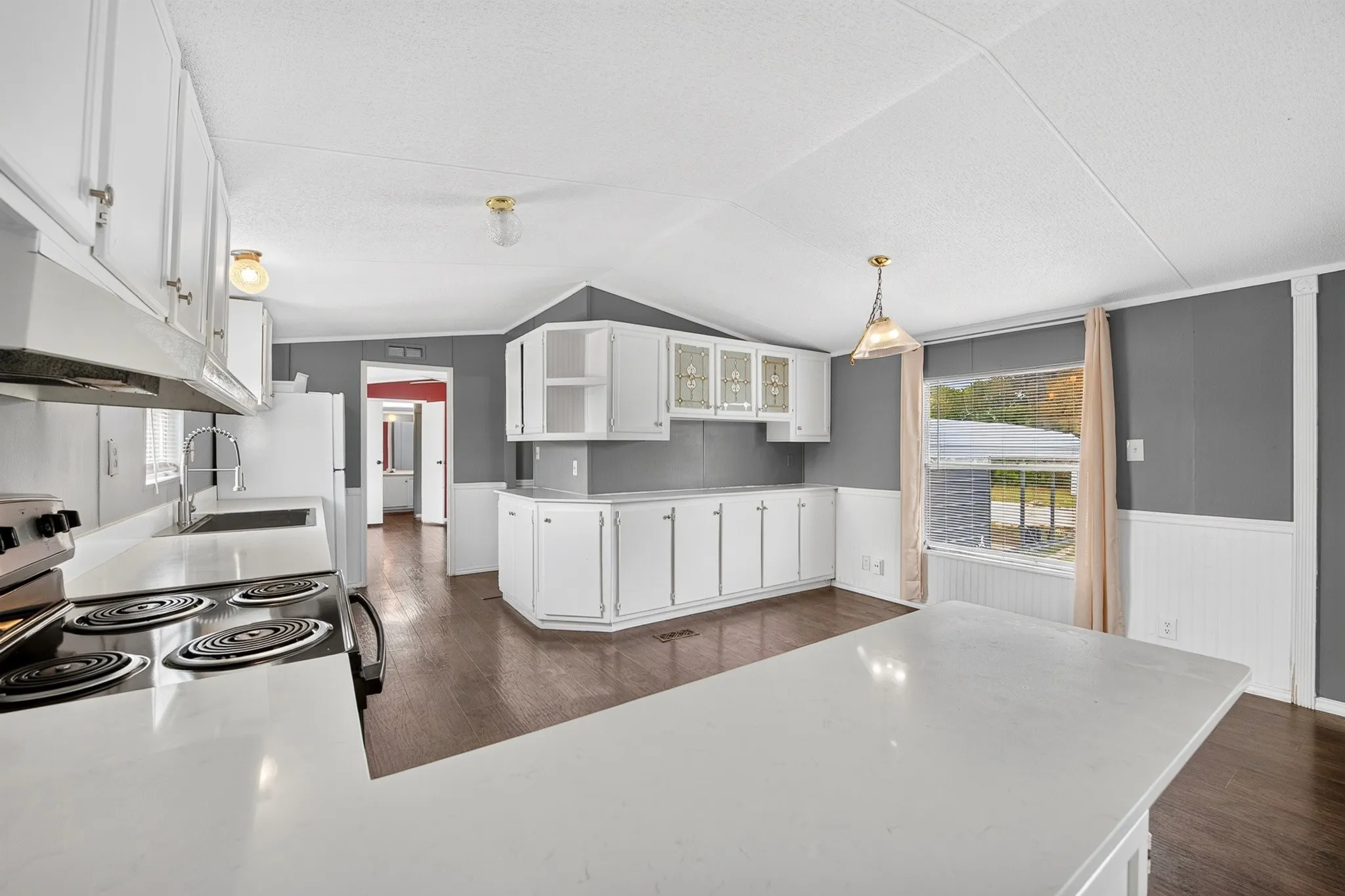 Kitchen featuring white cabinetry with glass-panel accents, solid-surface countertops, wood-finish flooring, and recessed lighting