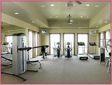 Exercise room featuring recessed lighting, a coffered ceiling with integrated ceiling fan, carpeted flooring, full-length wall mirrors, and multiple windows