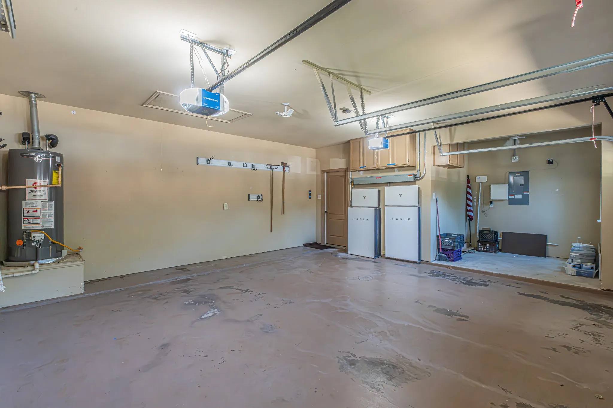 Attached 2.5 car garage featuring dual energy storage units, an overhead door opening system, and a gas water heater.