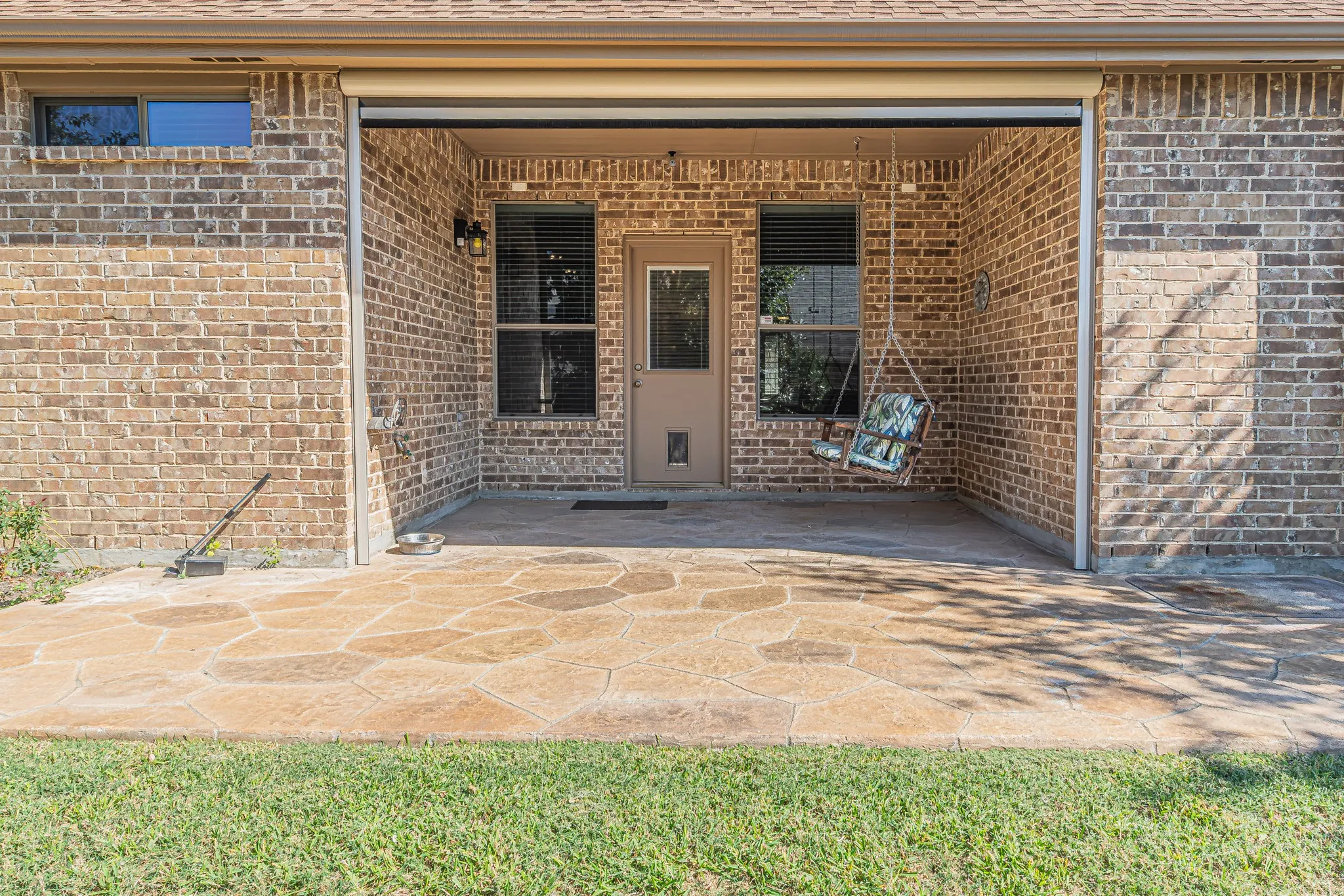 Covered patio featuring stamped concrete flooring, a full-height brick exterior, and a retractable solar screen
