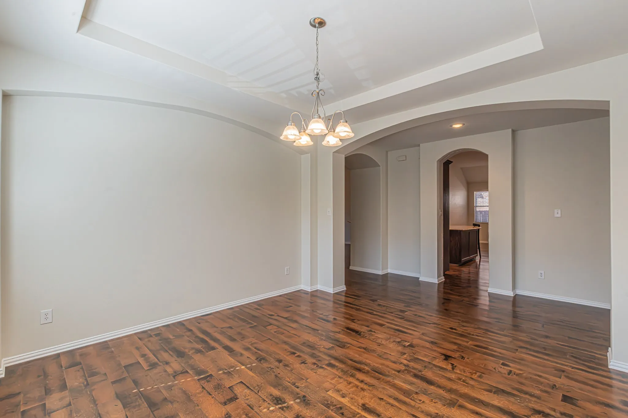 Or Formal Dining.Tray ceiling with recessed lighting, wood-finish flooring, multi-light chandelier, and arched wall openings. Flexible space!