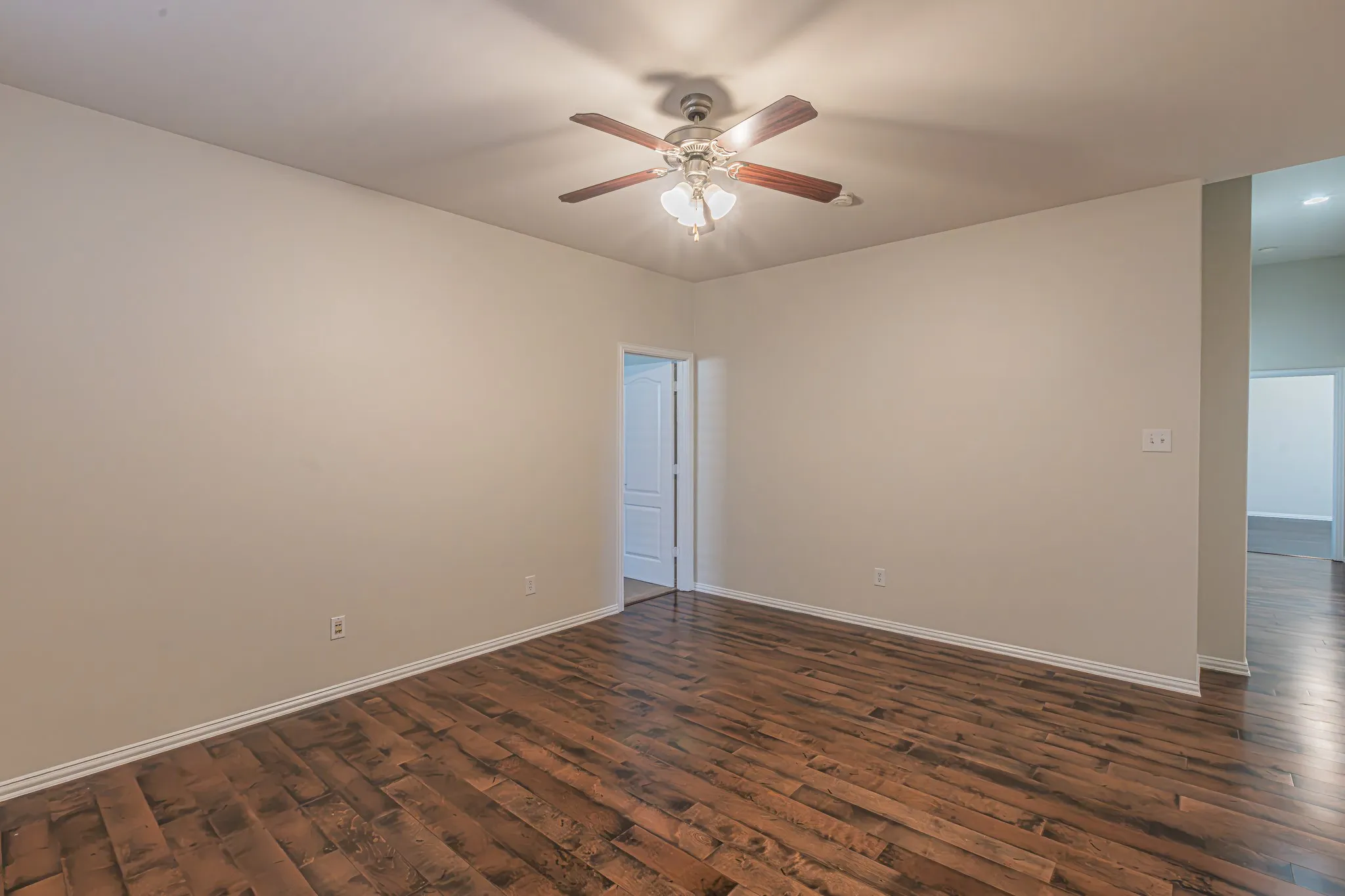 Room featuring wood-finish flooring, neutral wall paint, and a ceiling-mounted fan with integrated light fixture