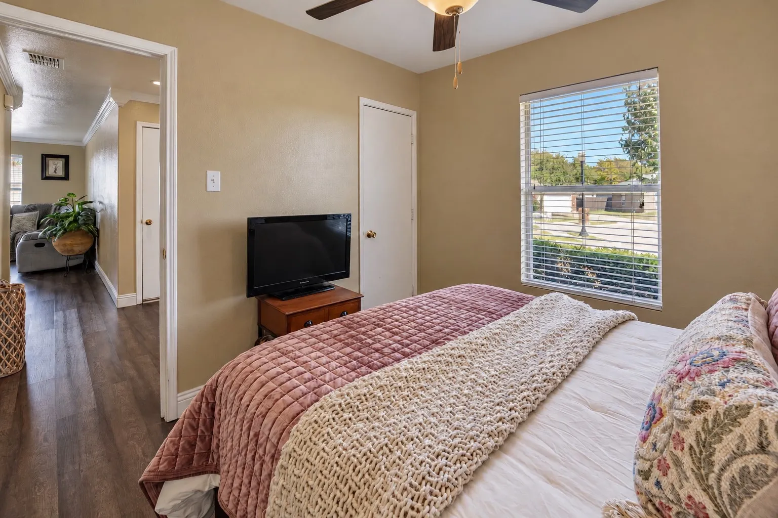 Neutral wall color, wood-finish flooring, ceiling fan with integrated lighting, and horizontal window blinds