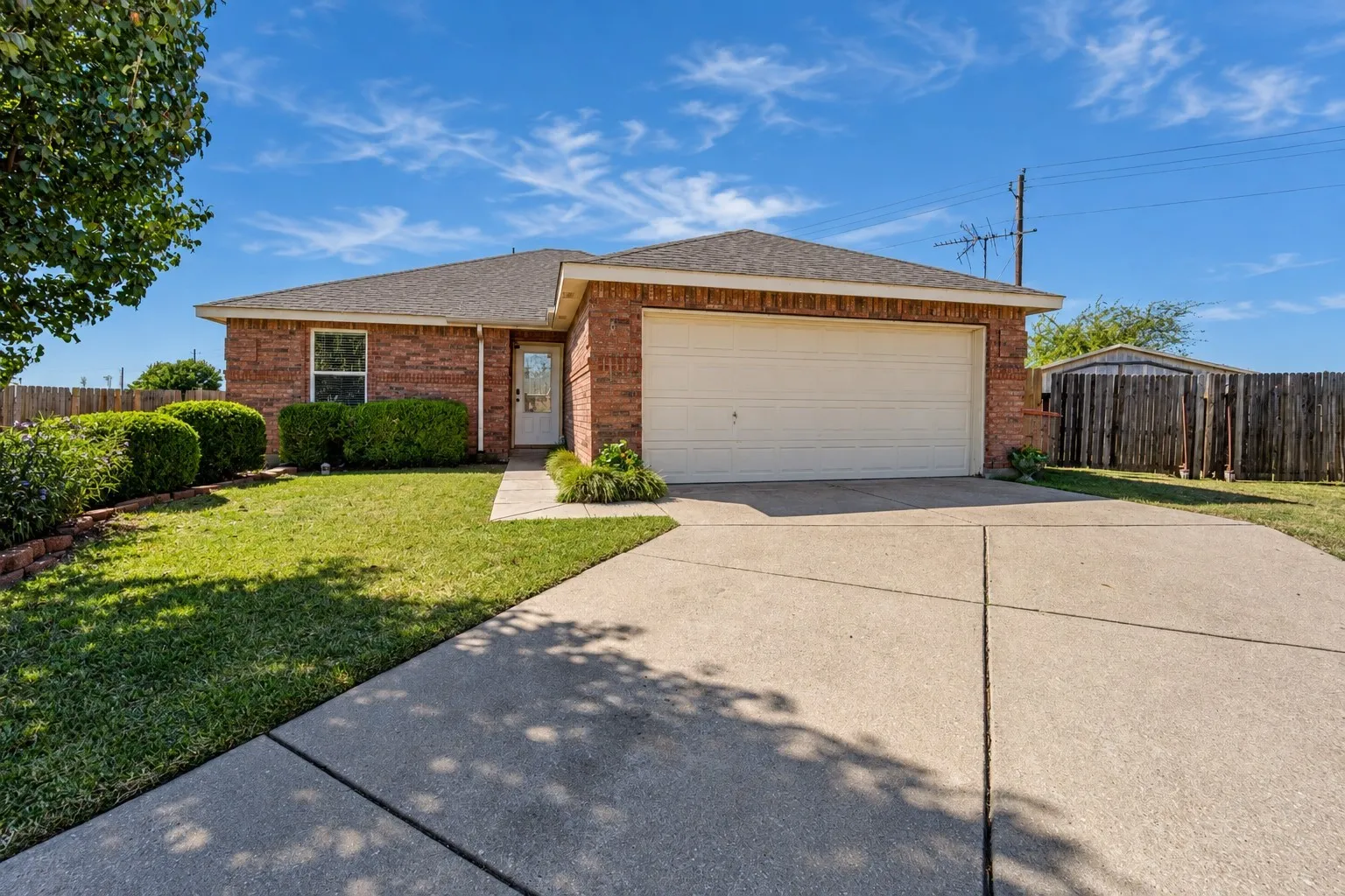 Single-story brick exterior featuring a concrete driveway, two-car garage, and manicured front lawn
