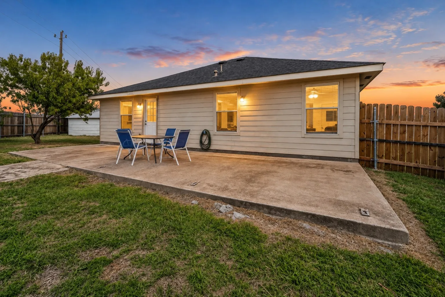 Exterior rear elevation featuring horizontal siding, a concrete patio, and a fenced backyard