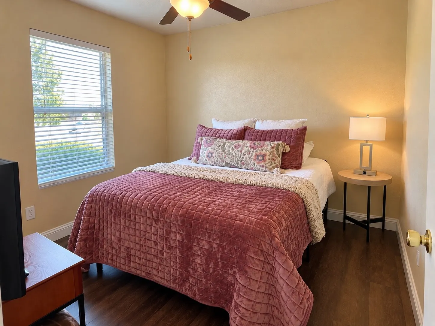Room featuring wood-finish flooring, a ceiling fan with integrated lighting, and a window with horizontal blinds