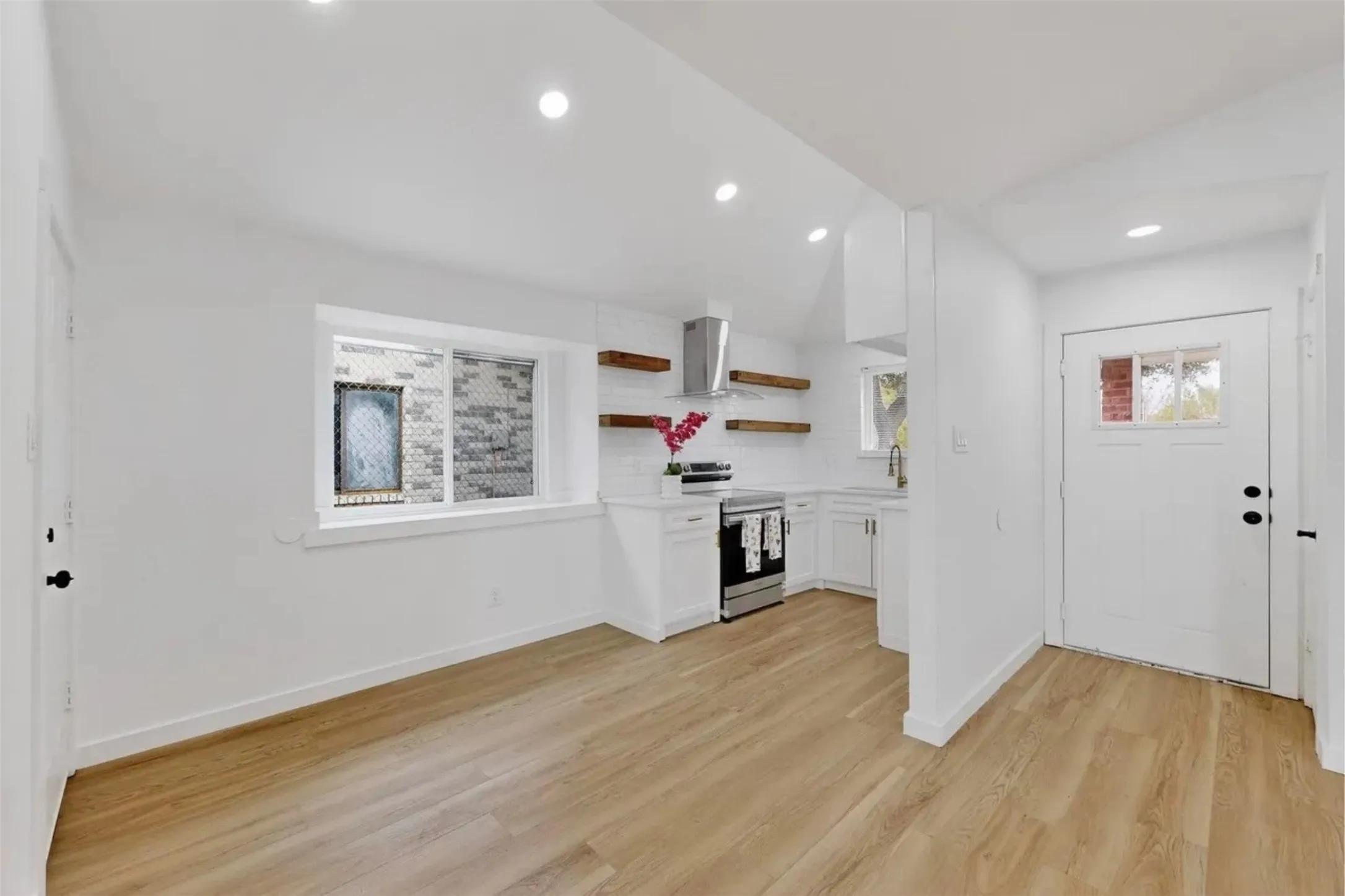Kitchen featuring white cabinetry, wood-finish flooring, recessed lighting, stainless steel appliances, and floating wood shelving