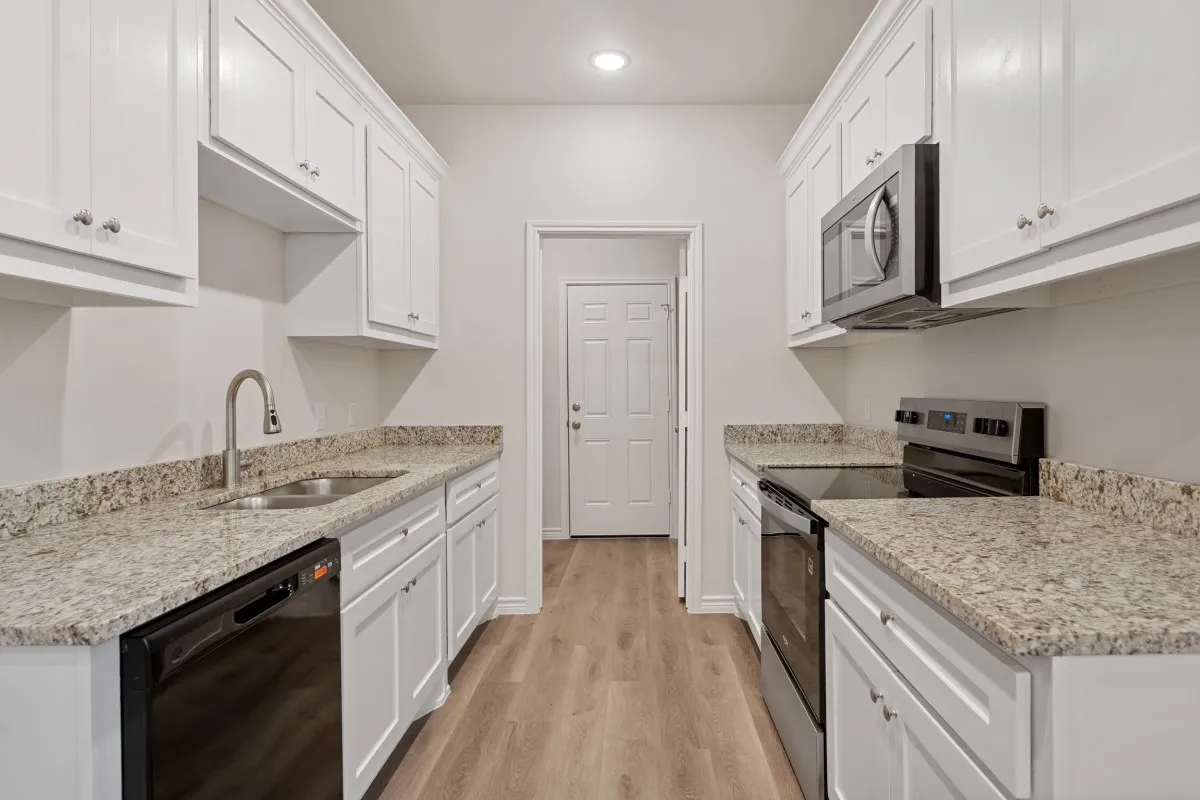 Kitchen featuring white Shaker-style cabinetry, stone-finish countertops, stainless steel appliances, and wood-finish flooring