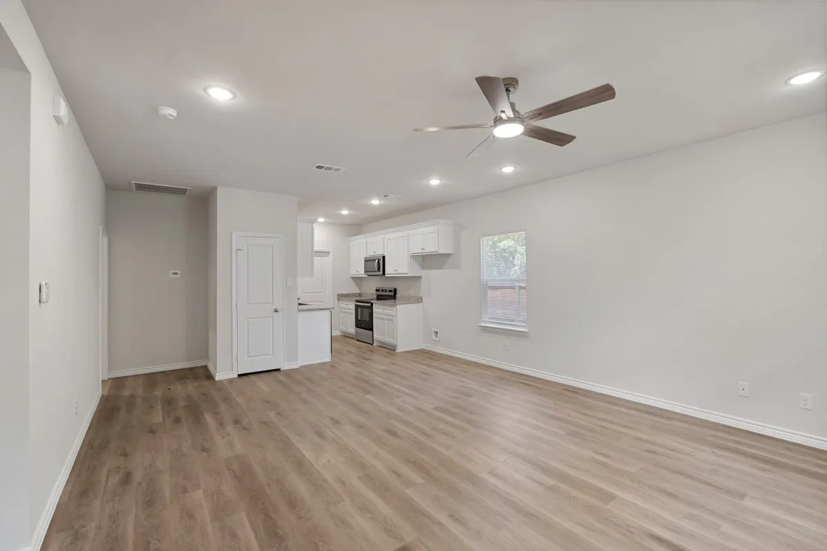 Open-concept interior featuring wood-finish flooring, recessed lighting, a ceiling fan, and white cabinetry paired with stainless steel appliances