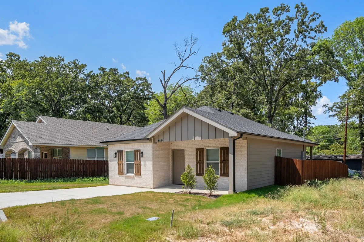 Single-story residence featuring a brick and vertical siding facade, gable roofline, decorative window shutters, and a concrete driveway