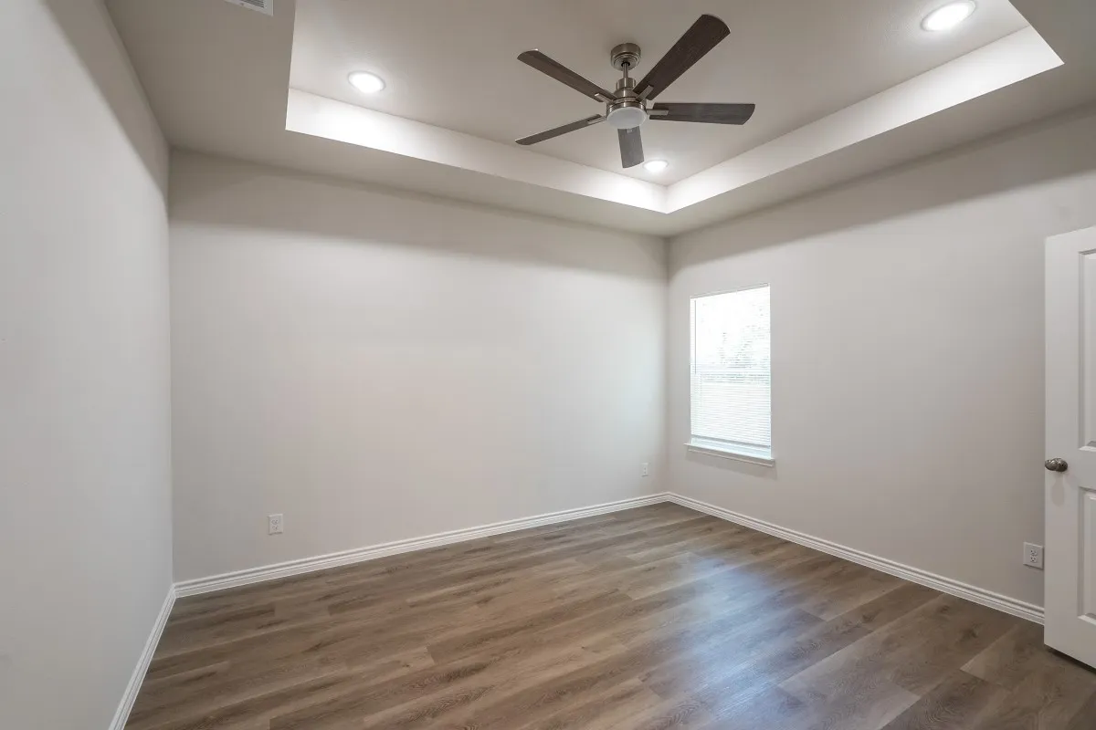 Tray ceiling featuring a brushed nickel ceiling fan, recessed lighting, and wood-finish flooring