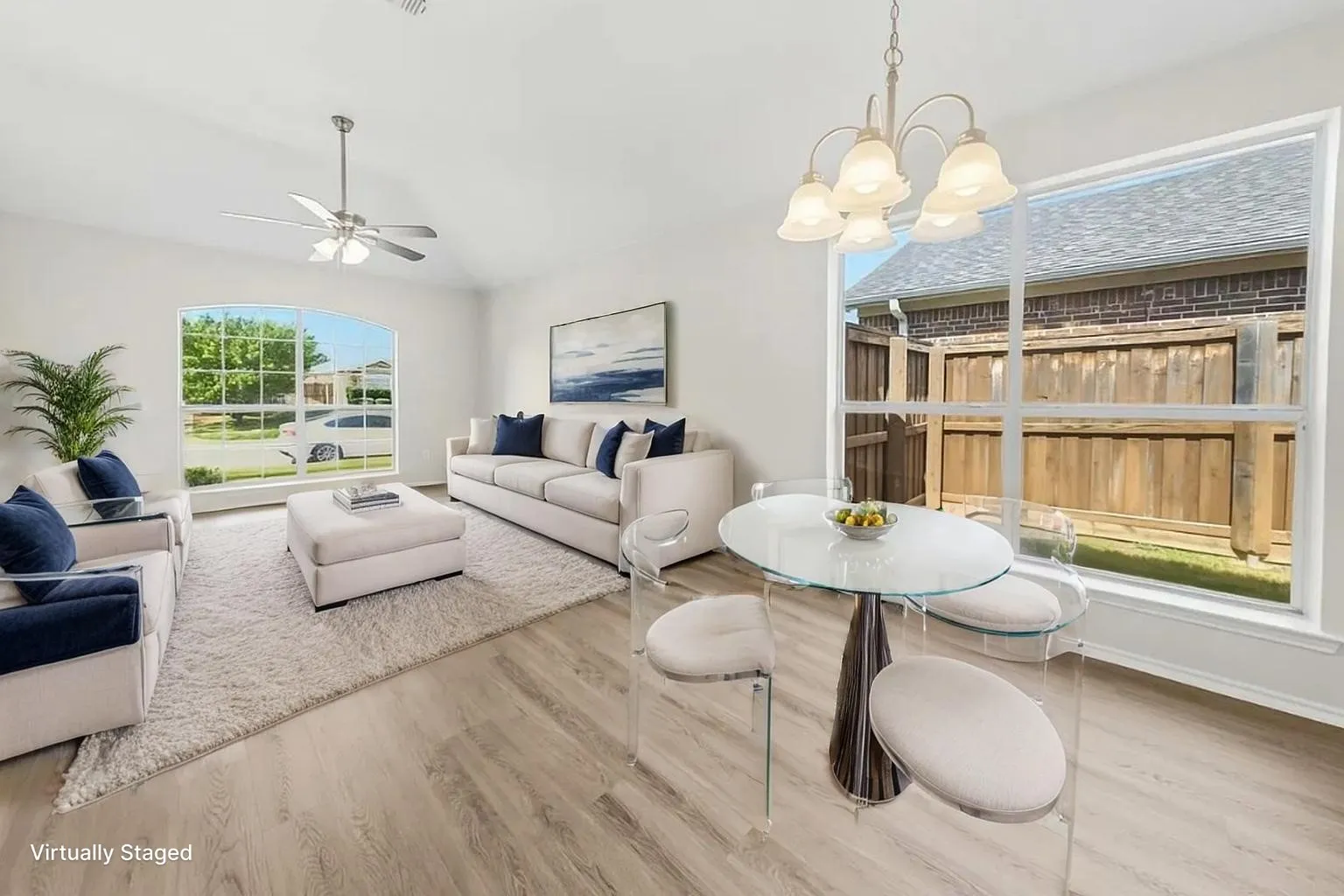 Open-concept living space featuring wood-finish flooring, vaulted ceilings, a ceiling fan, and large windows with natural light