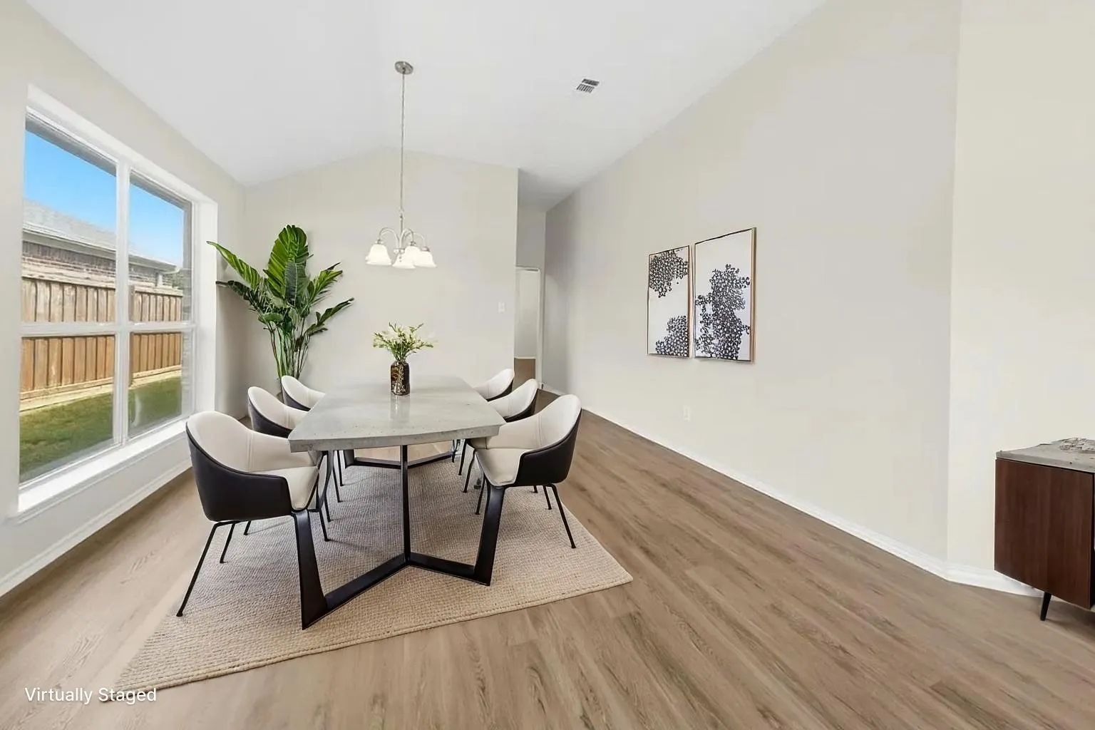 Vaulted ceiling, wood-finish flooring, and large windows providing natural light