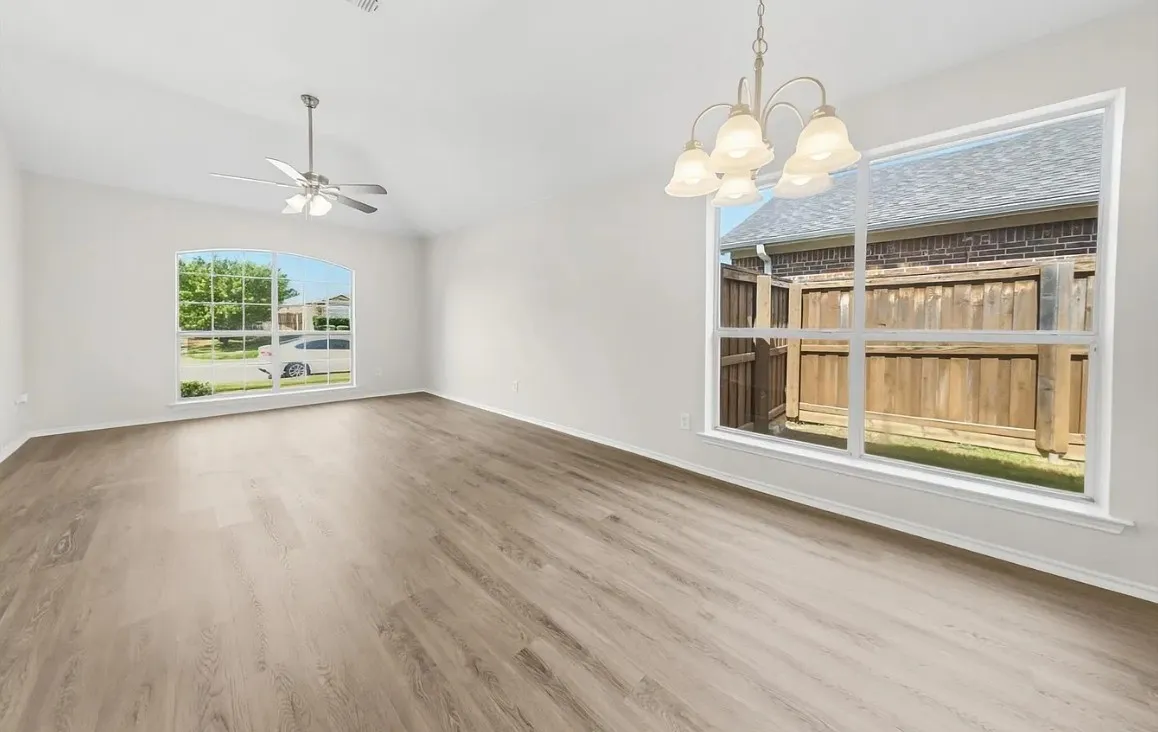Living space featuring vaulted ceilings, wood-finish flooring, multi-pane windows, a central ceiling fan, and a multi-arm chandelier