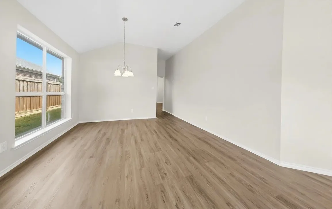 Vaulted ceilings, wood-finish flooring, neutral wall palette, and multi-light pendant fixture
