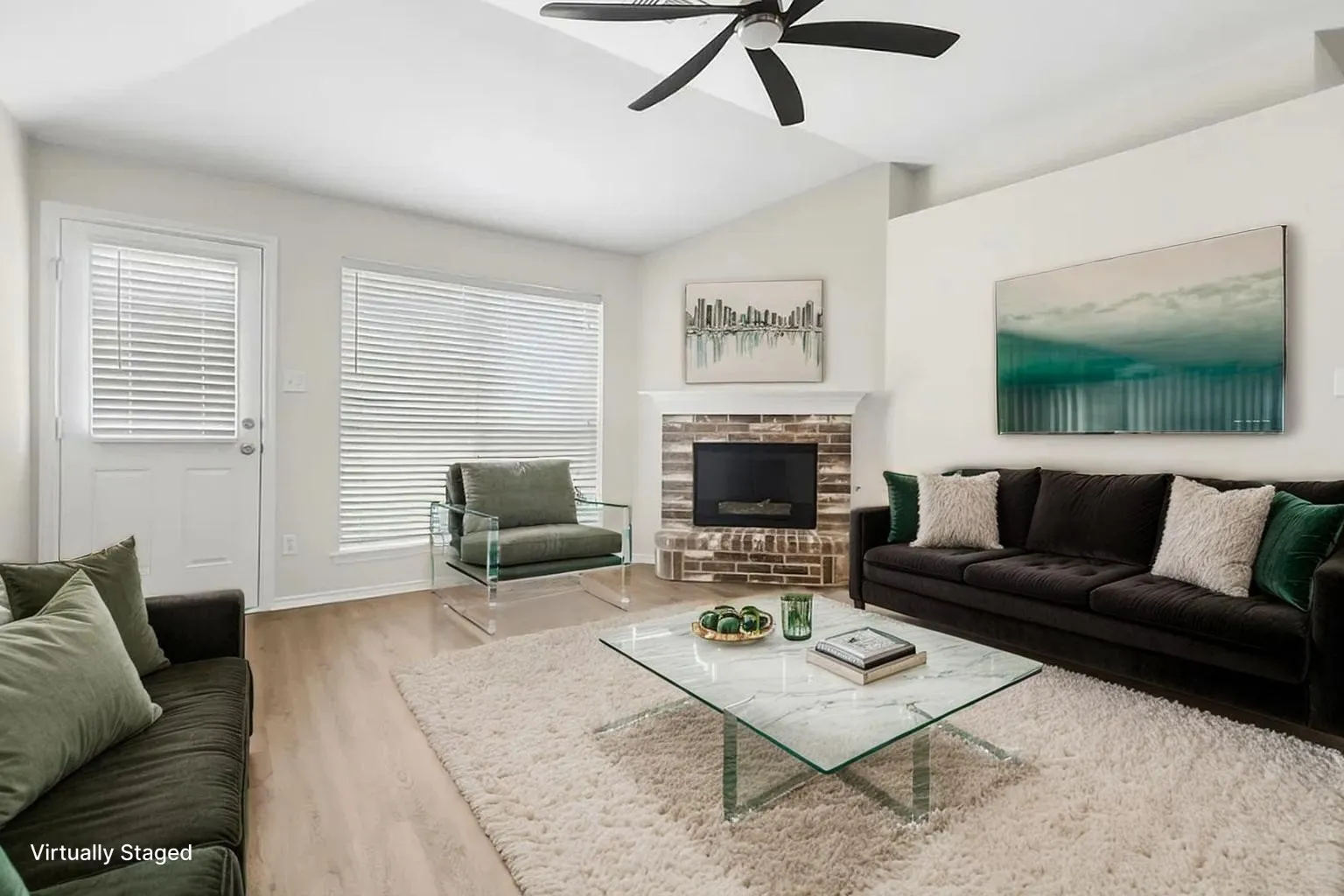 Vaulted ceilings with a ceiling fan, brick fireplace surround, wood-finish flooring, and natural light from multiple windows