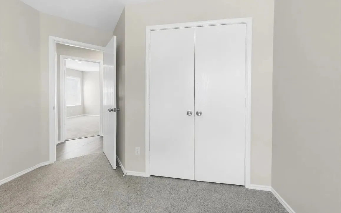 Double-door closet with spherical hardware, neutral wall finish, and wall-to-wall carpeting
