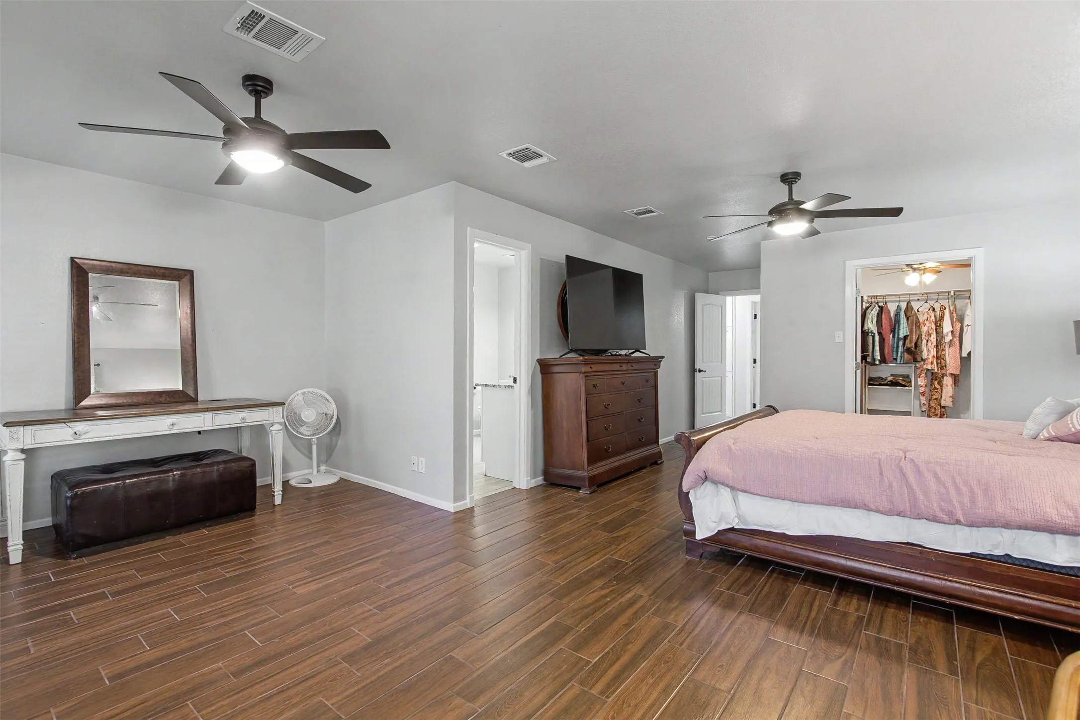Wood-finish tile flooring, dual ceiling fans with integrated lighting, and neutral wall tones