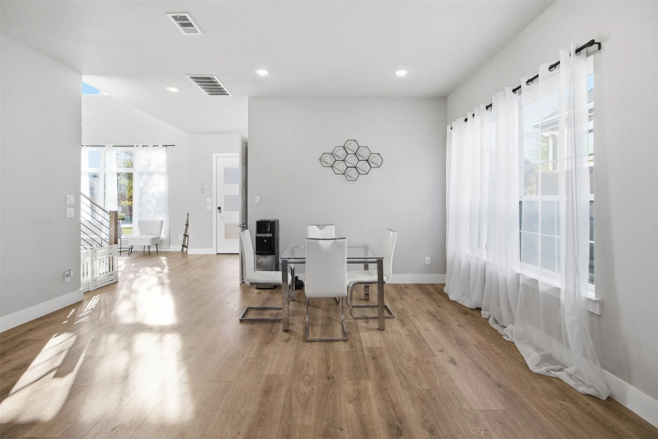 Open-concept interior featuring wood-finish flooring, recessed lighting, and large windows with horizontal muntins
