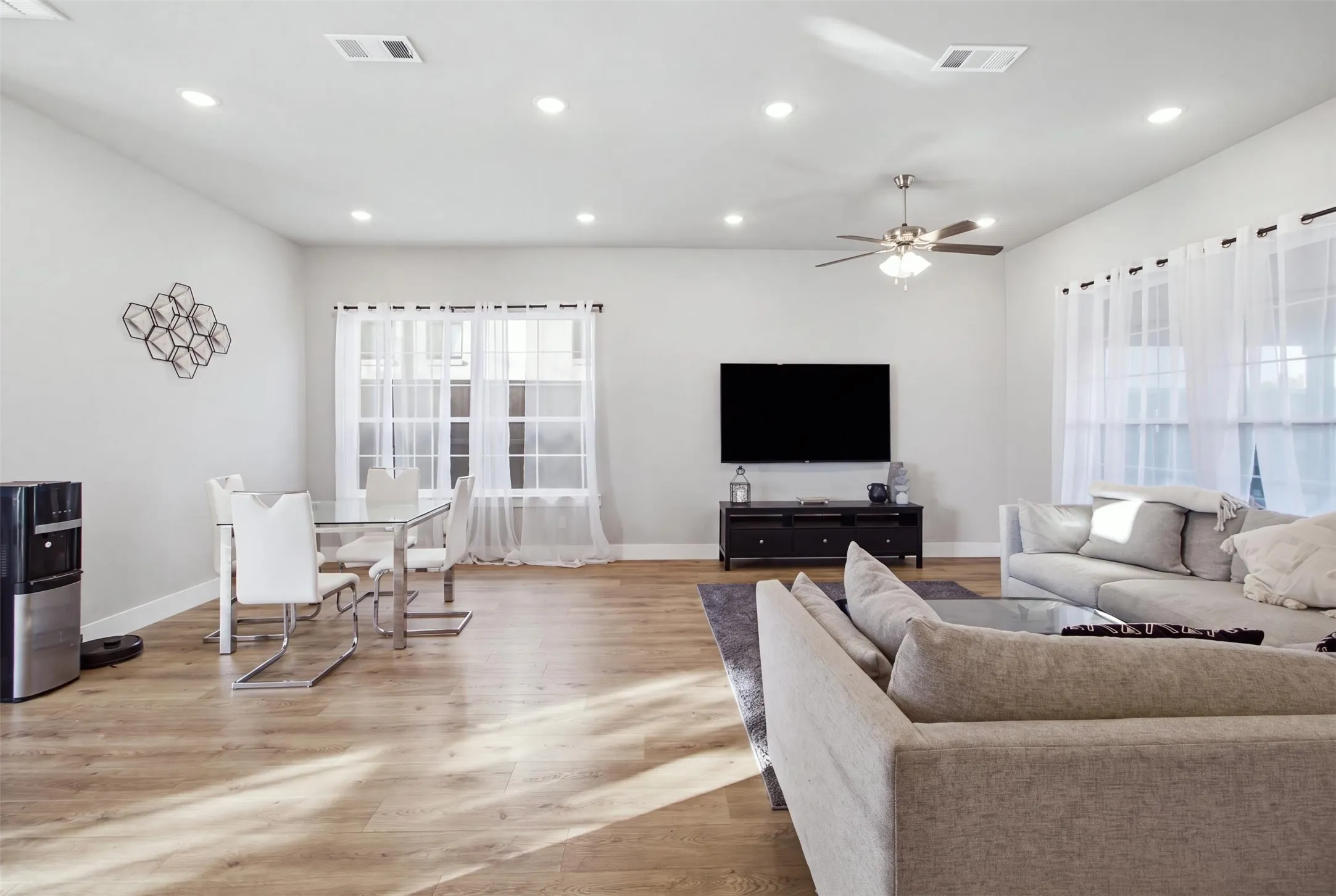 Open-concept living space featuring wood-finish flooring, recessed lighting, and a ceiling fan