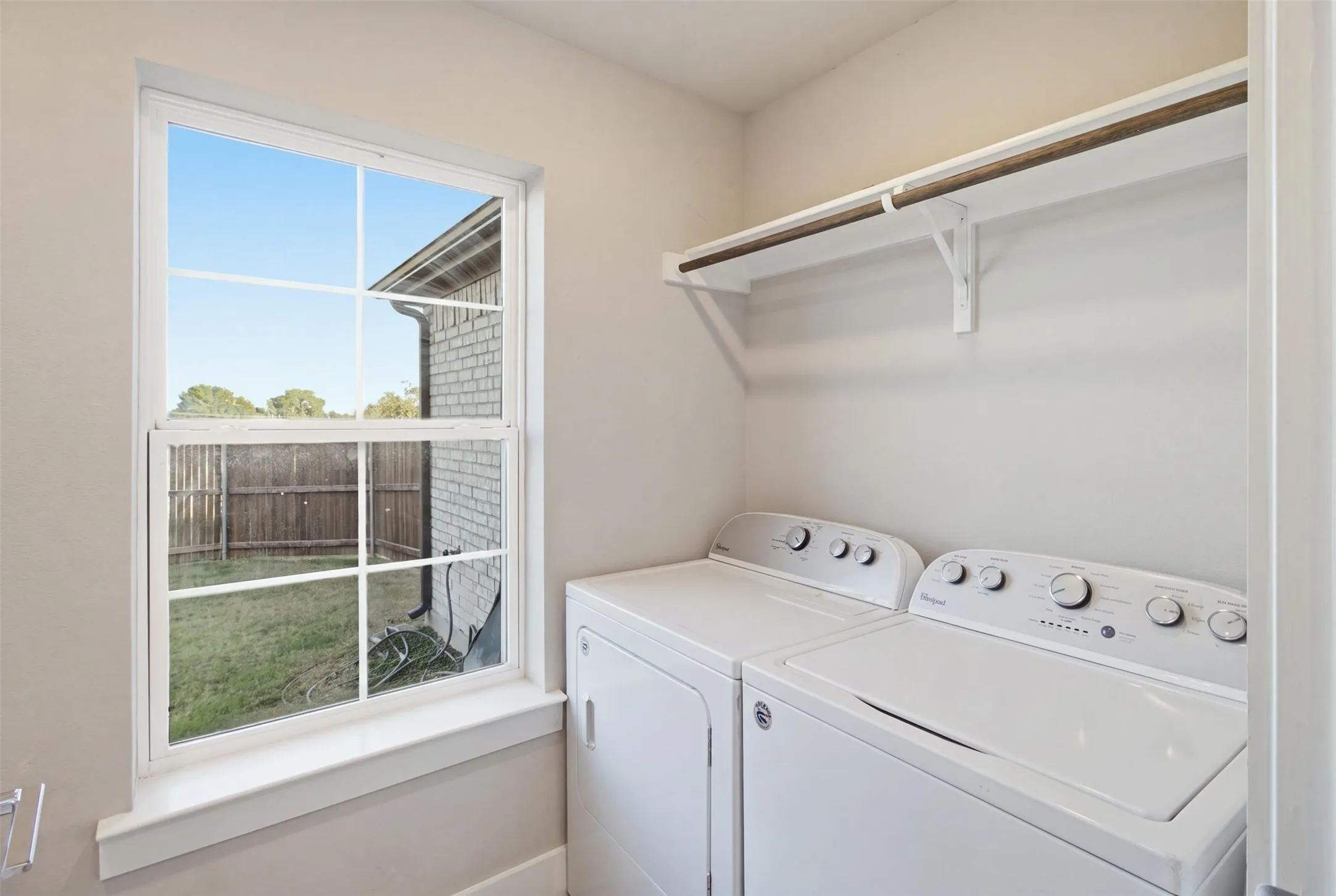 Utility space featuring a multi-pane window, white-finish built-in shelving, and white-finish laundry appliances