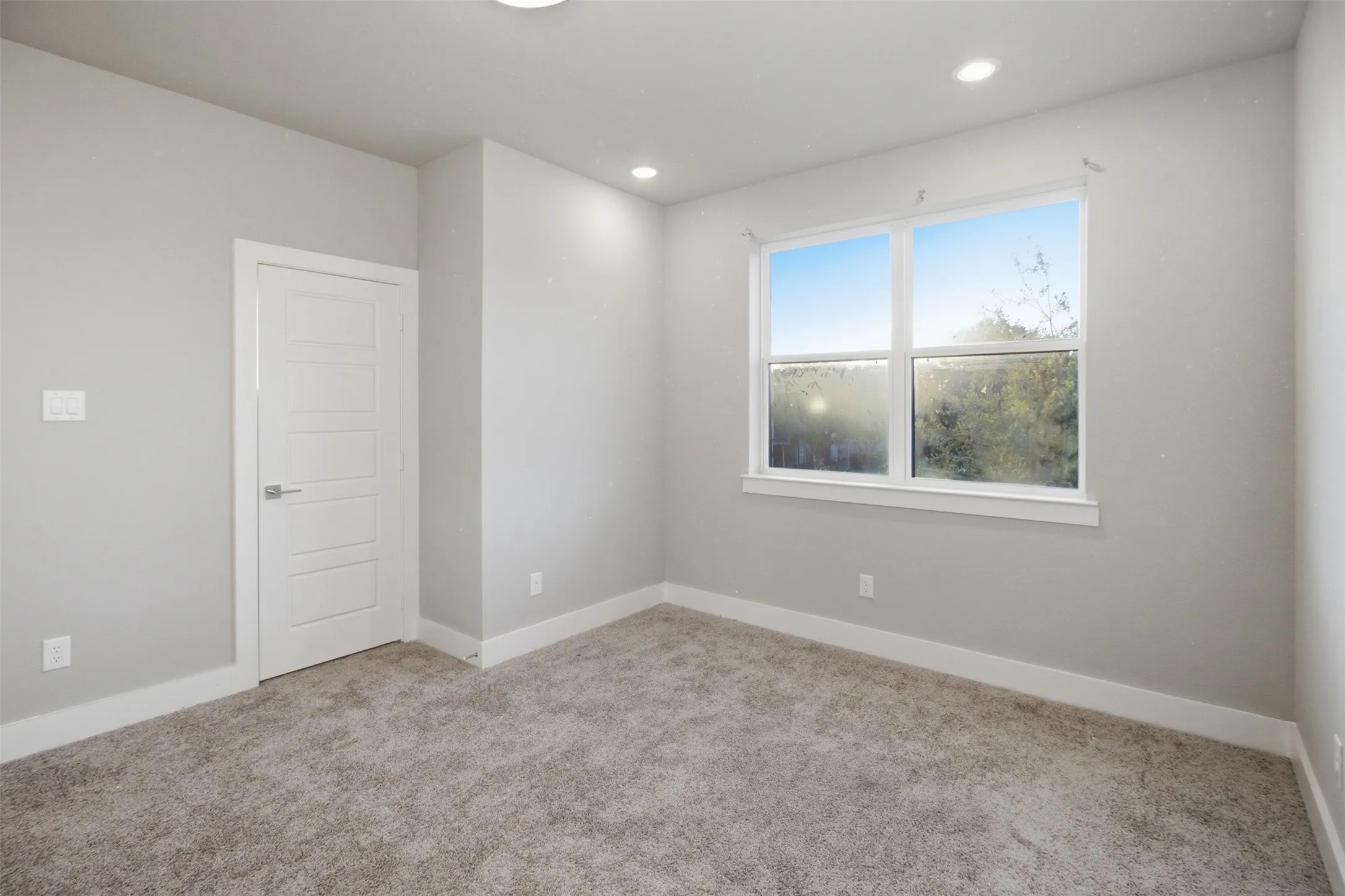 Neutral-toned interior featuring wall-to-wall carpeting, recessed ceiling lighting, and a multi-panel interior door