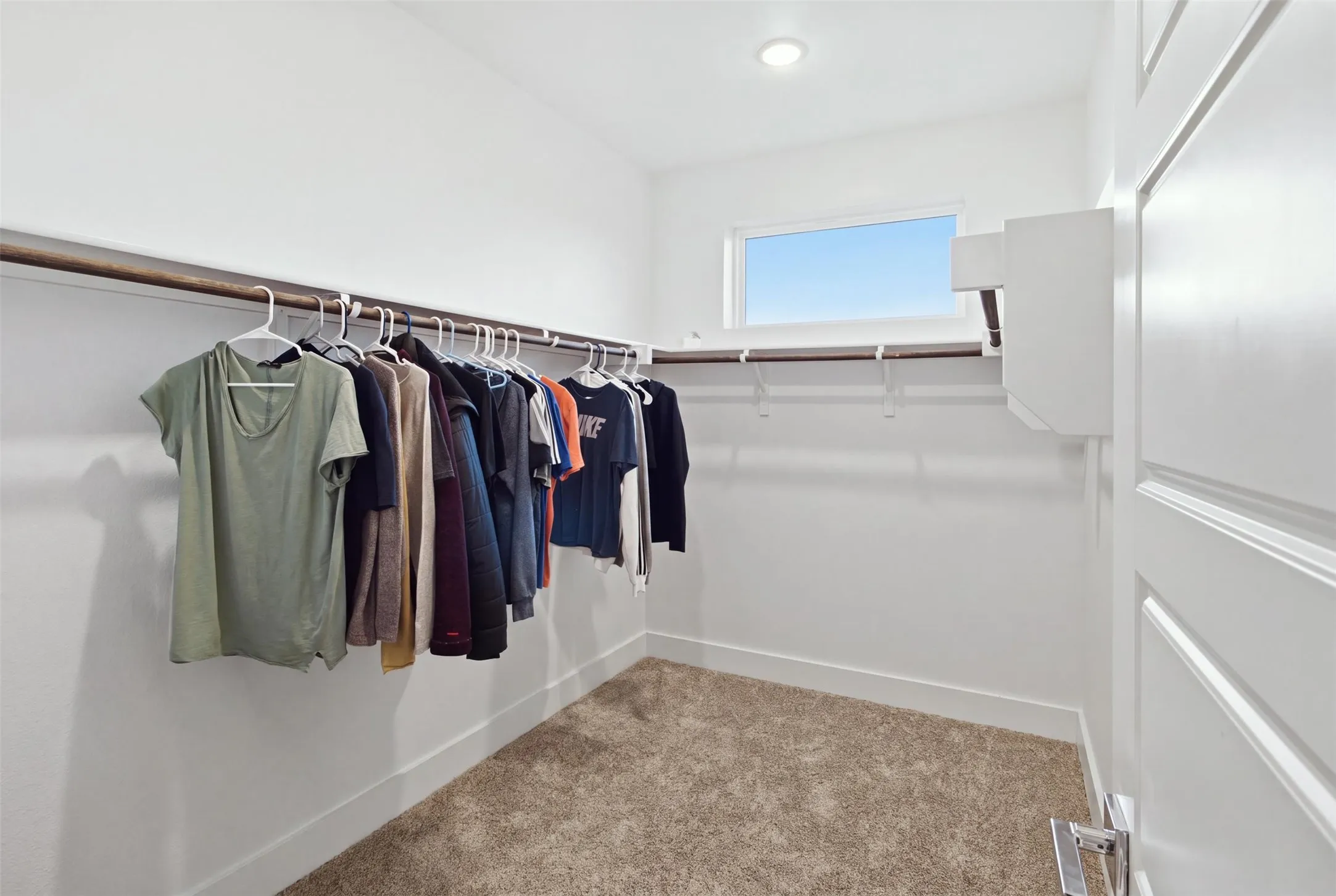 Walk-in closet featuring wall-to-wall carpeting, recessed ceiling lighting, horizontal window, and dual-tier hanging rods