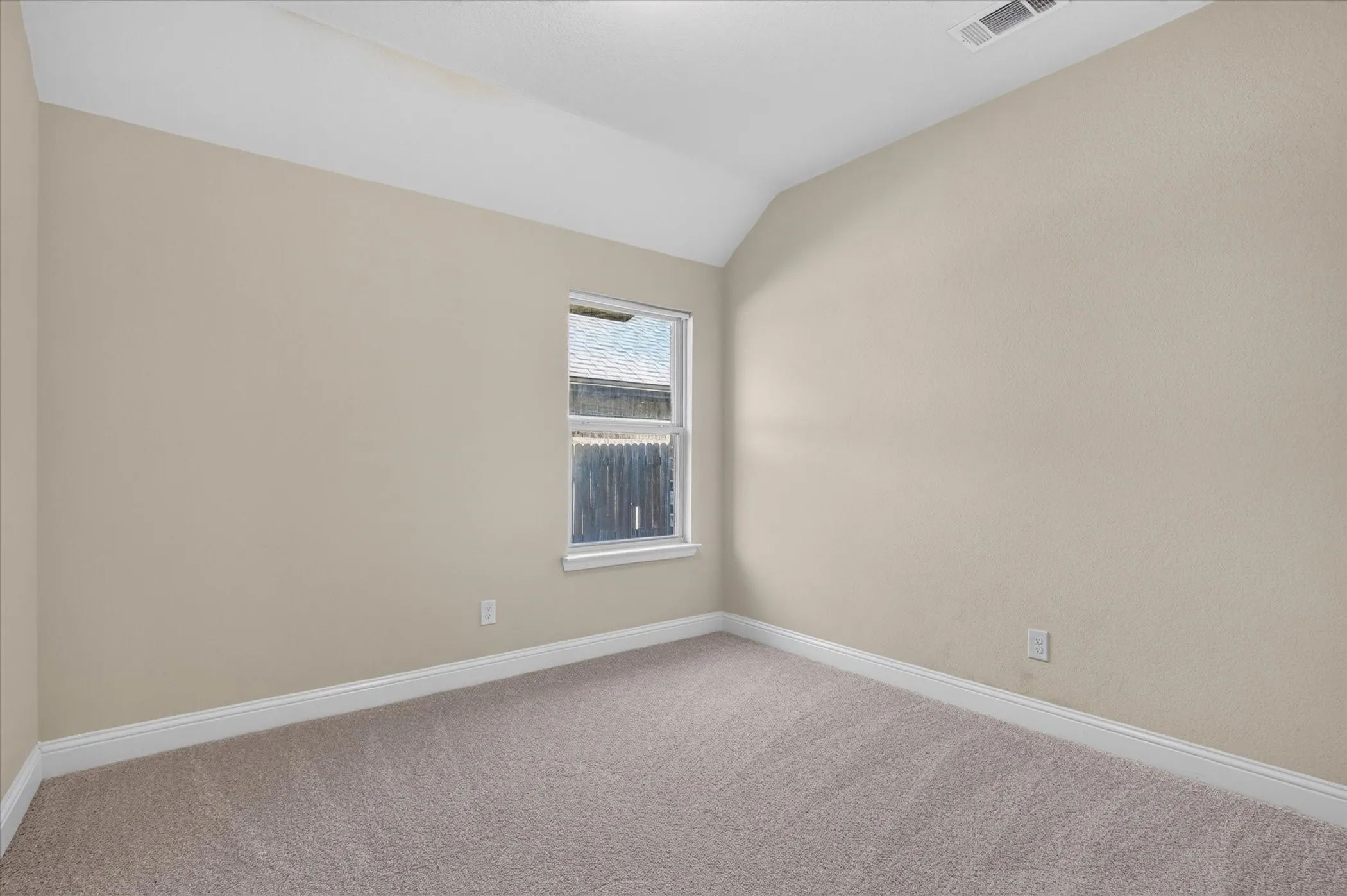 Neutral-toned room featuring a vaulted ceiling, wall-to-wall carpeting, and a single-pane window