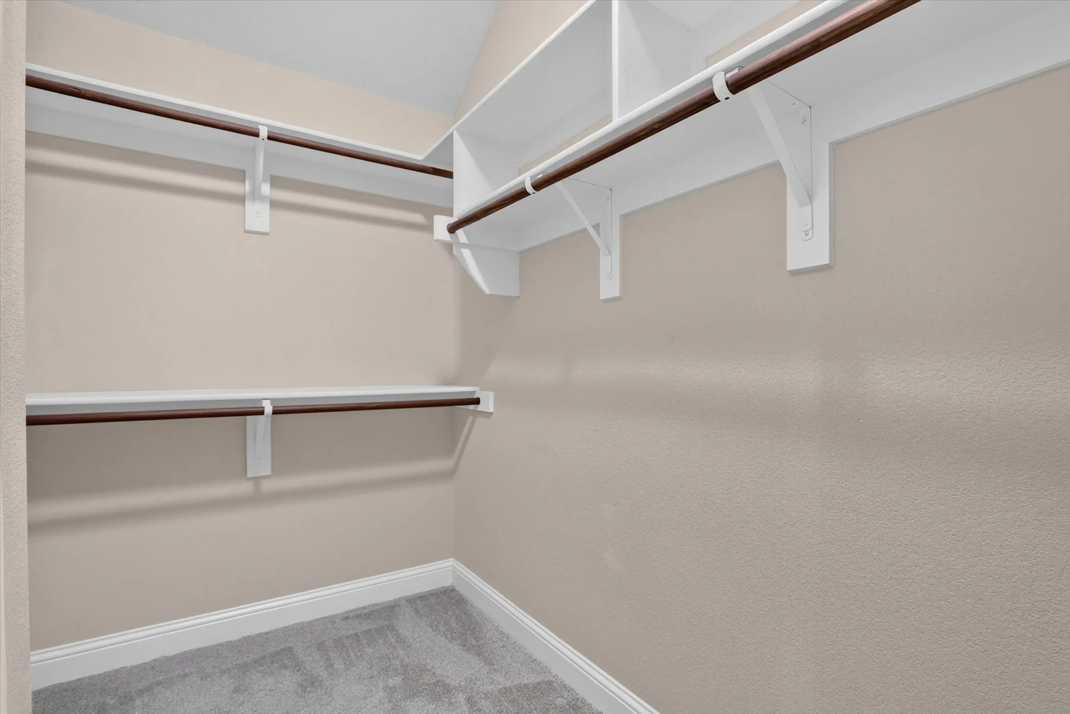 Walk-in closet featuring multi-level white wood shelving and integrated rods
