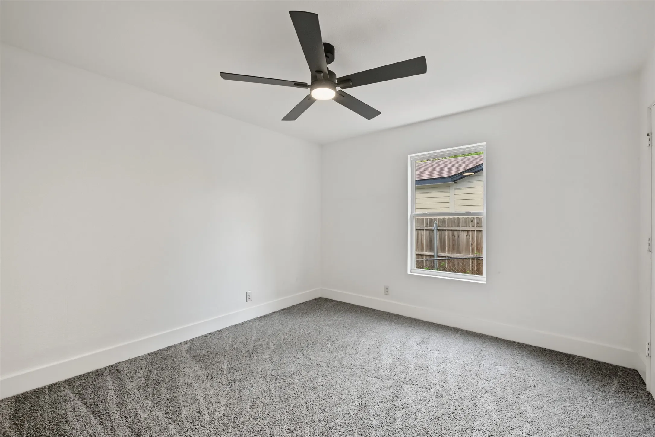 Neutral wall tones, grey carpeting, and a matte black ceiling fan with integrated lighting